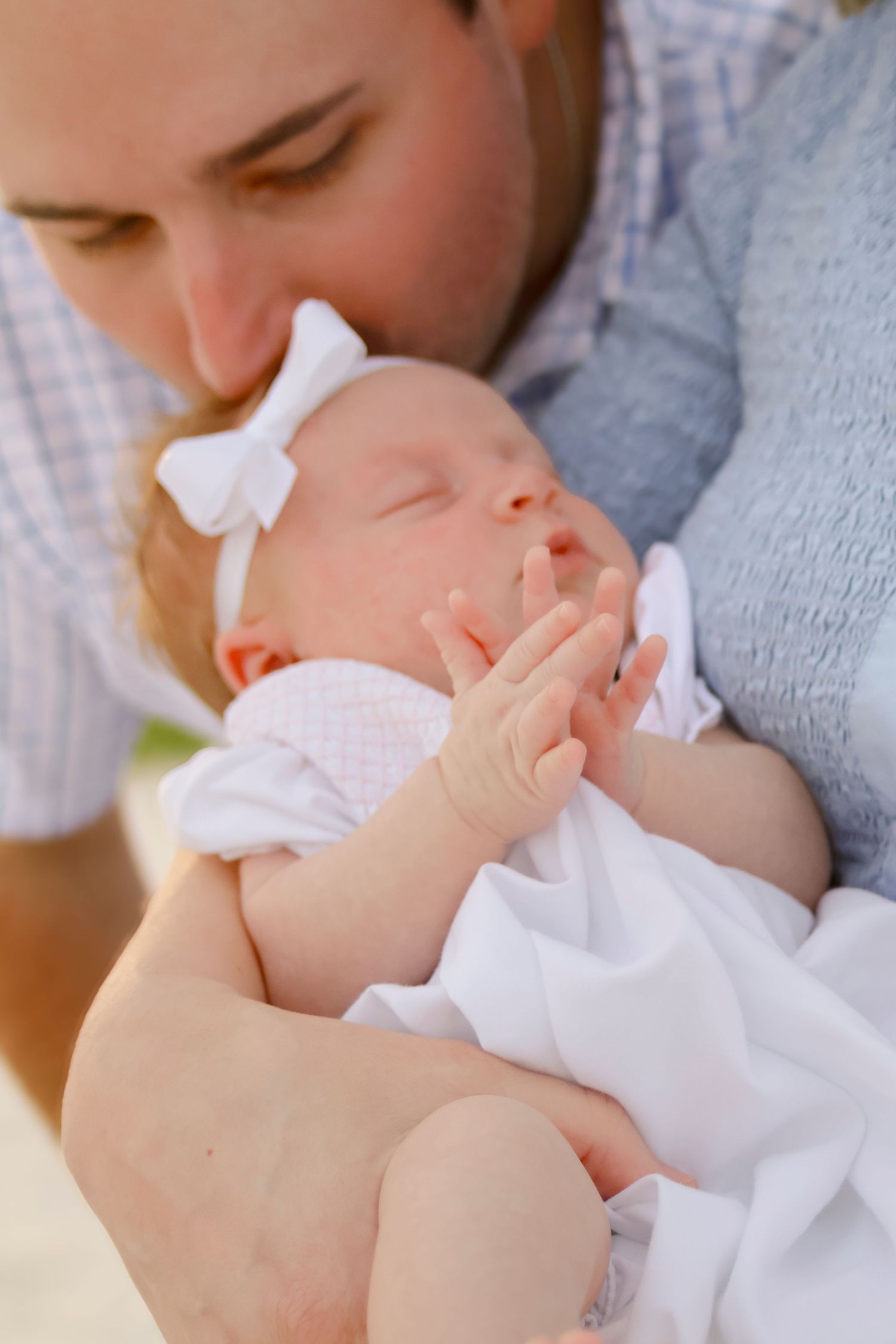 A baby in a white dress sleeps peacefully in close-up family portrait series.