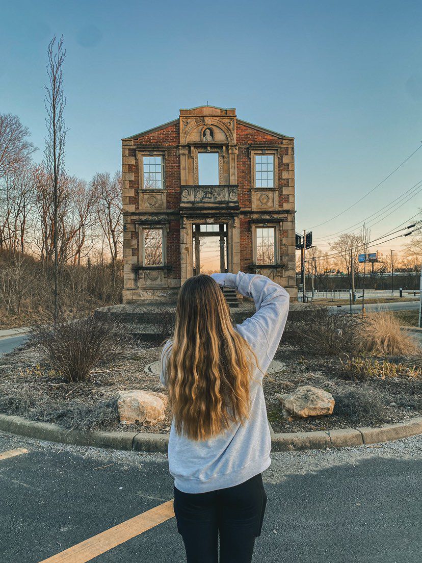 A series of photos showing someone in a white sweater viewing an abandoned brick building with large windows at sunset.