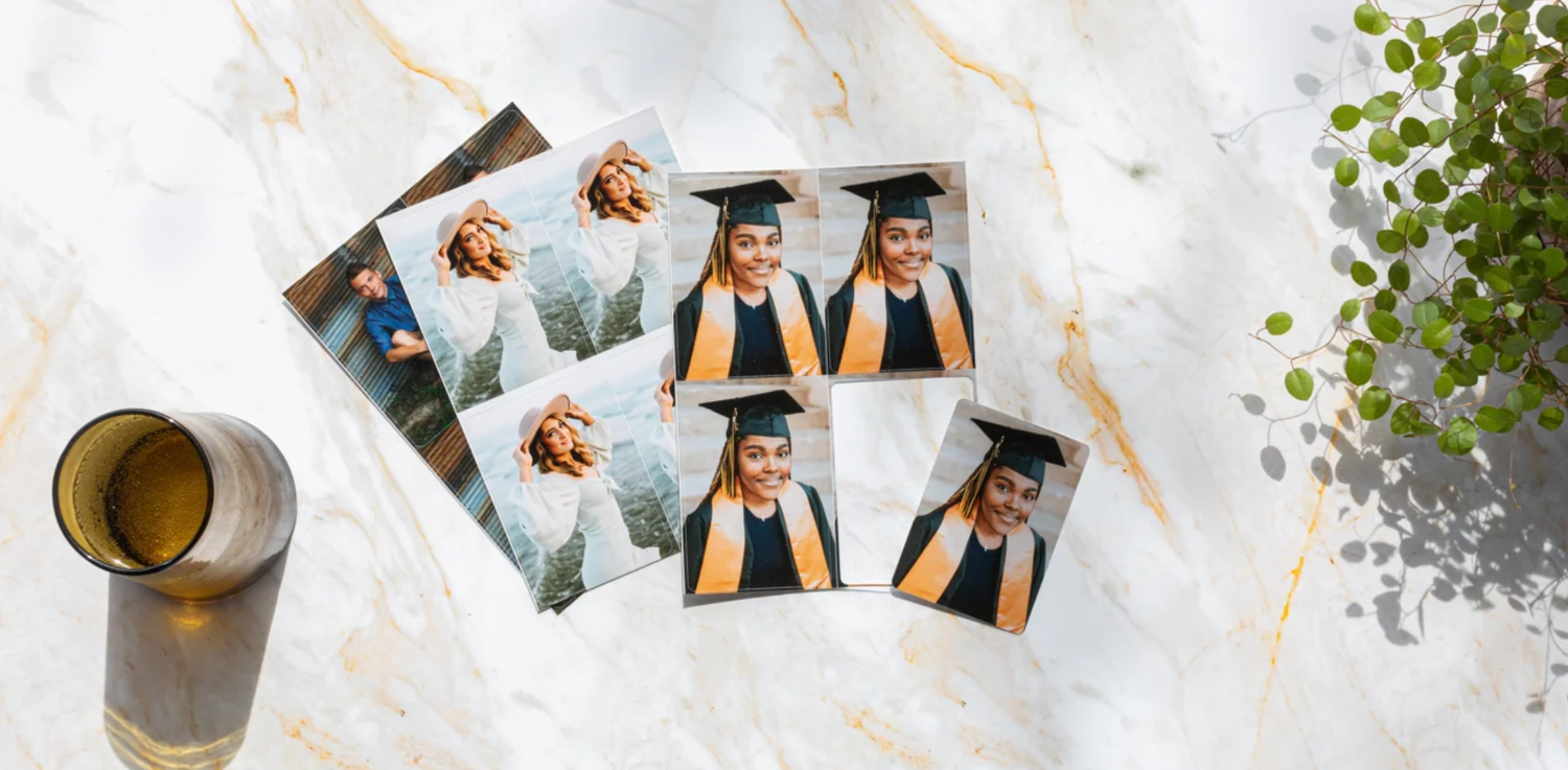 Students celebrate at graduation ceremony with mortarboards tossed into the air against a blurred nature background.