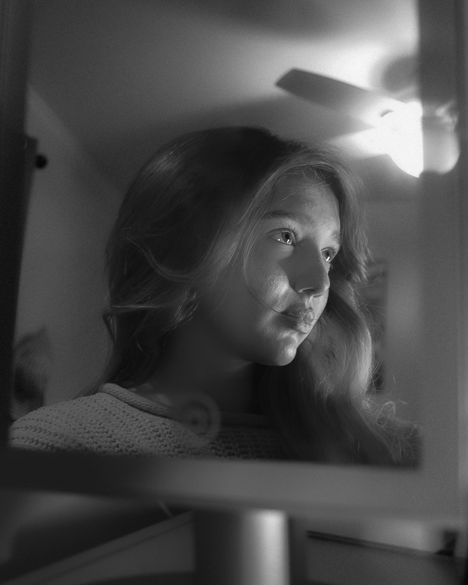 Moody black and white portrait with dramatic side lighting creating shadows and contrast.