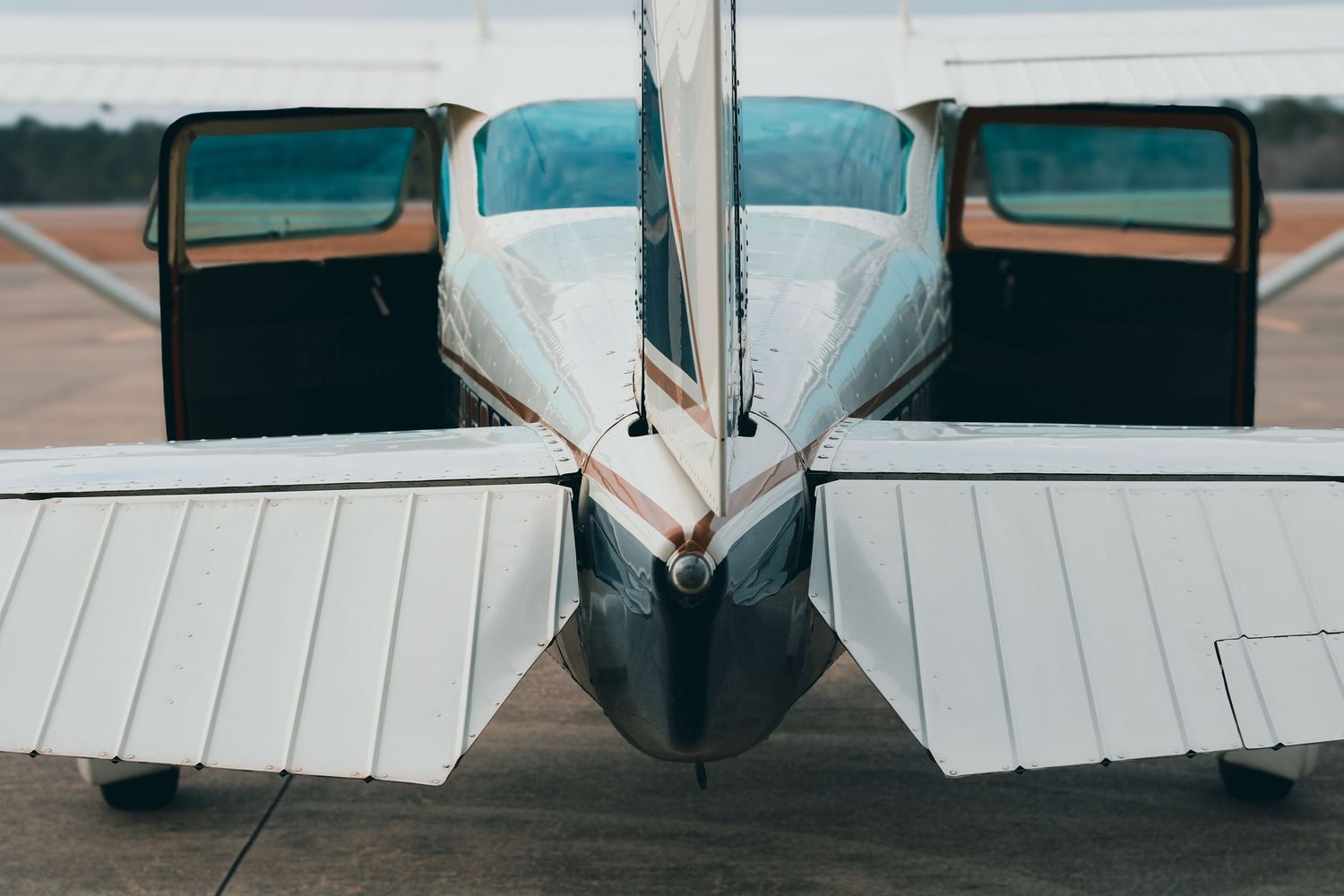 Close-up view of a small aircraft's tail section with white wings and teal accents on the tarmac.