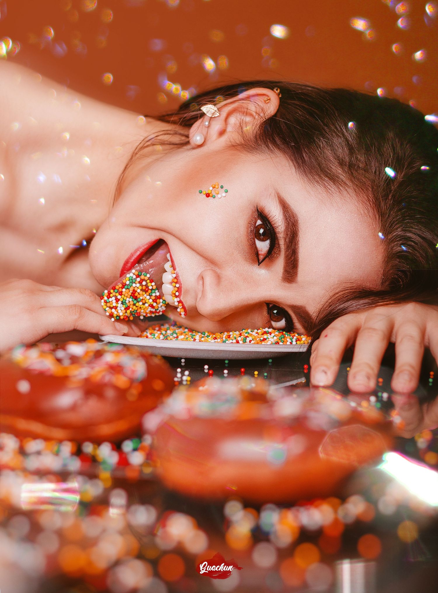 Creative portrait with colorful sprinkles and donuts in vibrant reddish lighting.