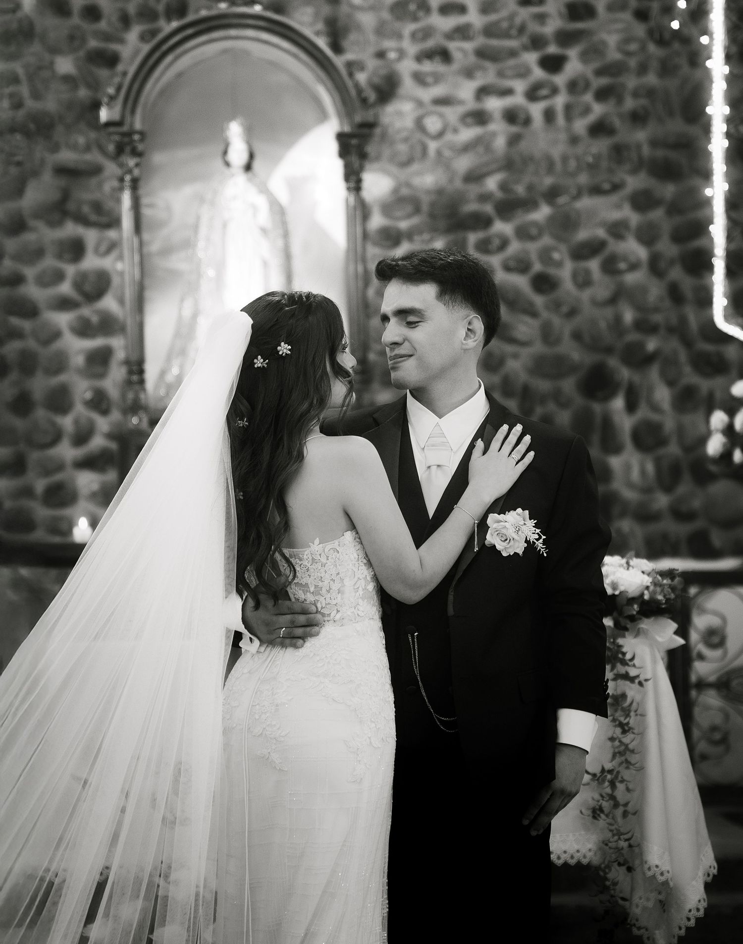 A romantic black and white wedding photo sequence showing a bride and groom sharing tender kisses against a stone wall backdrop.