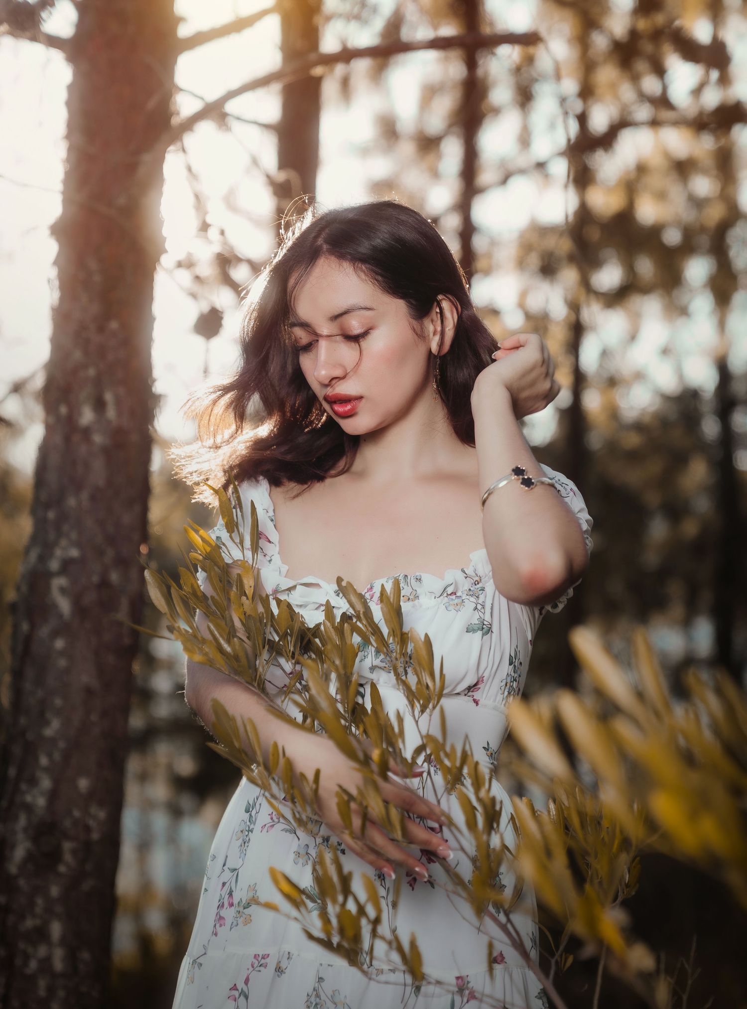 Dreamy outdoor portrait session in white floral dress among trees at sunset.