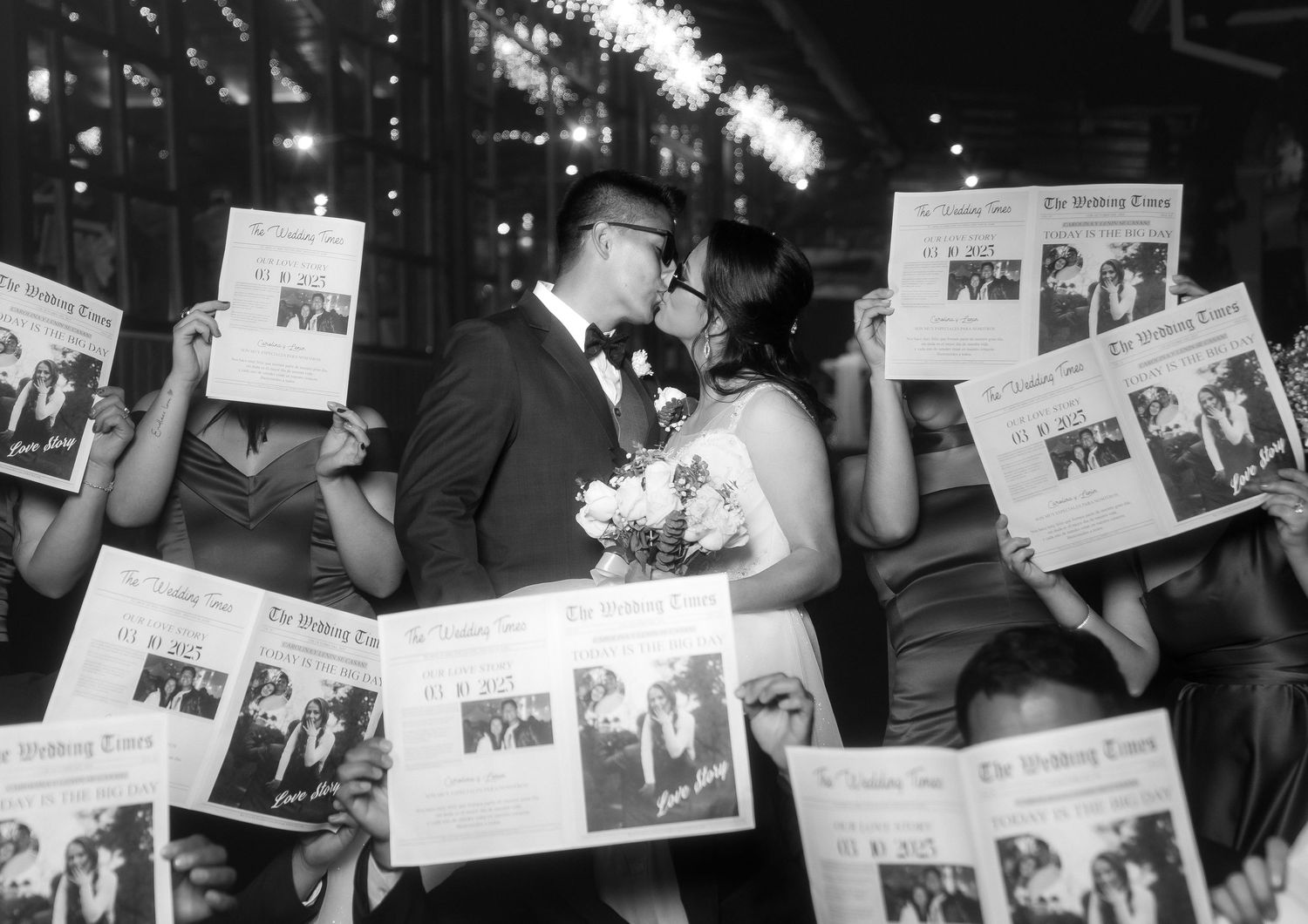 A black and white photo shows a crowd of people holding up newspapers and reading them in an animated manner.