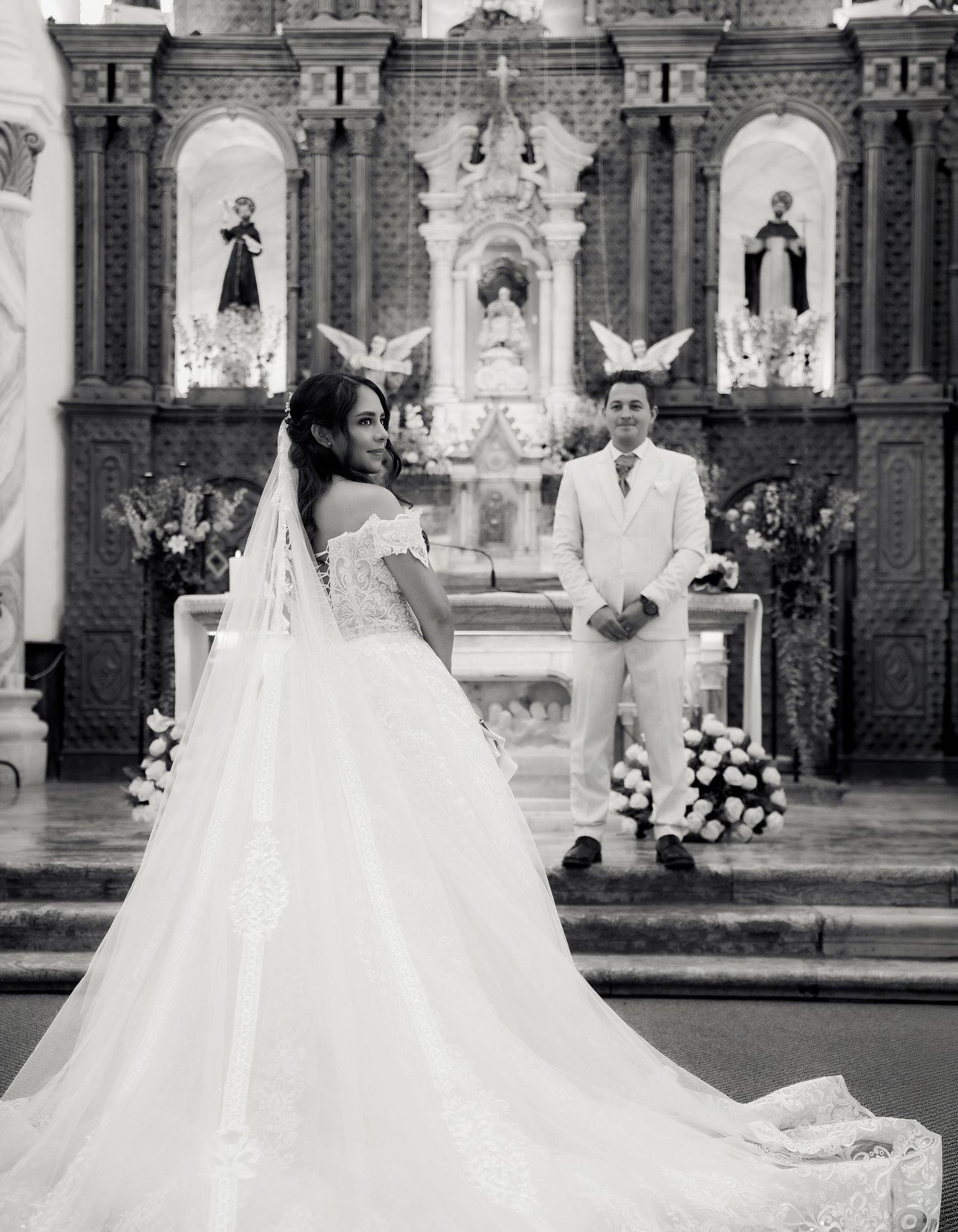 A traditional church wedding ceremony with a couple at the altar surrounded by ornate religious decor and floral arrangements.