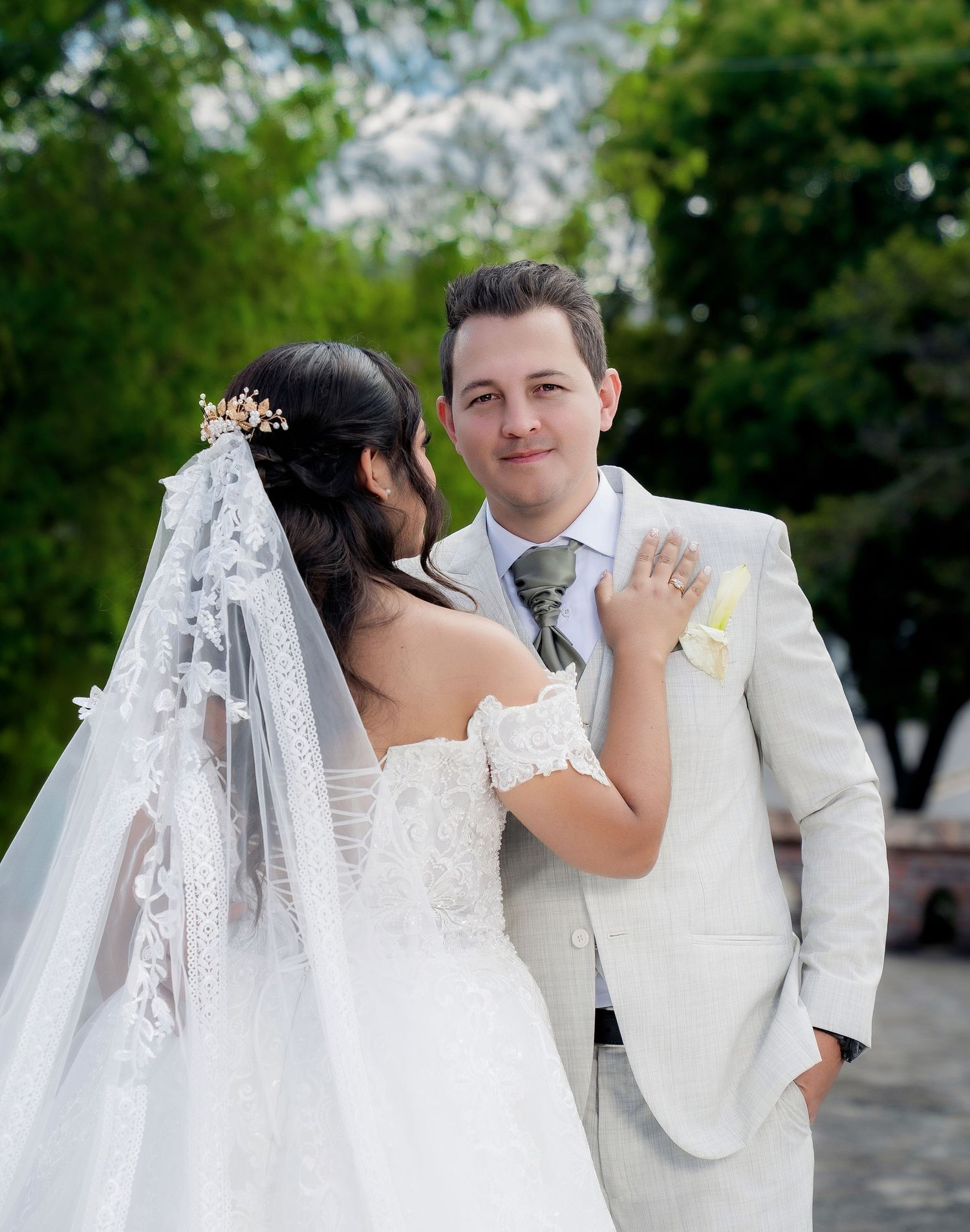 A romantic wedding couple in white attire share intimate moments in an outdoor garden setting.