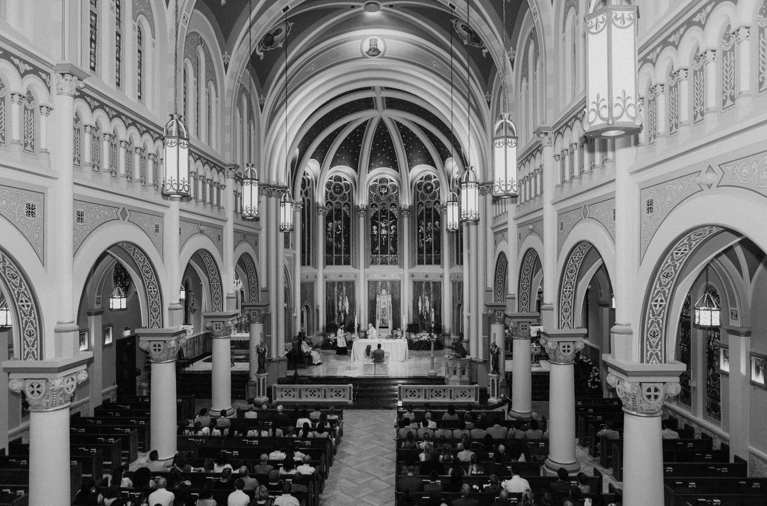 Black and white aerial view of a grand cathedral wedding ceremony with guests seated in ornate pews.