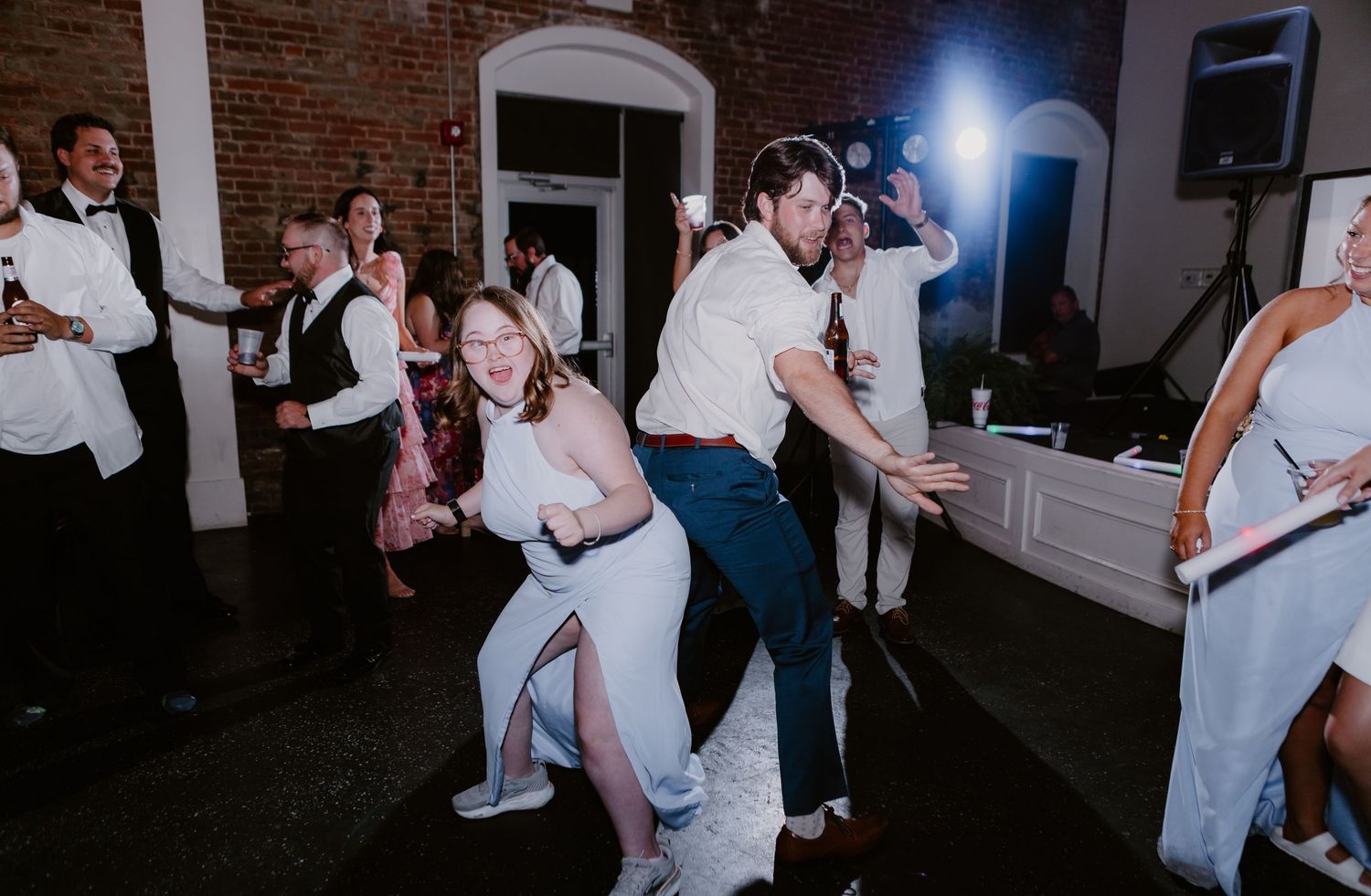 Bride and groom perform a fun limbo dance move with guests at their lively wedding reception.