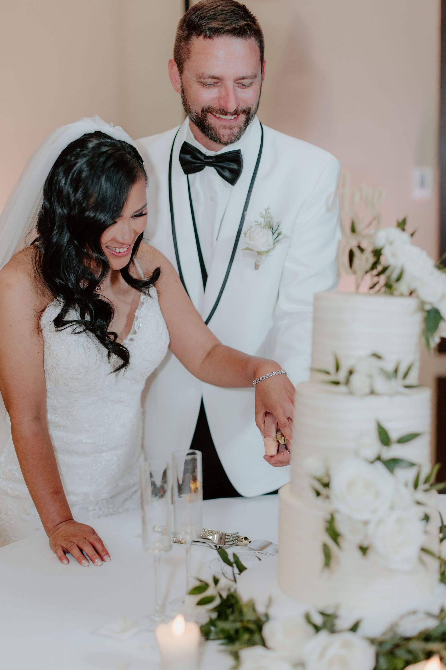 A couple shares a joyful moment together during their wedding reception with white floral decor in the background.
