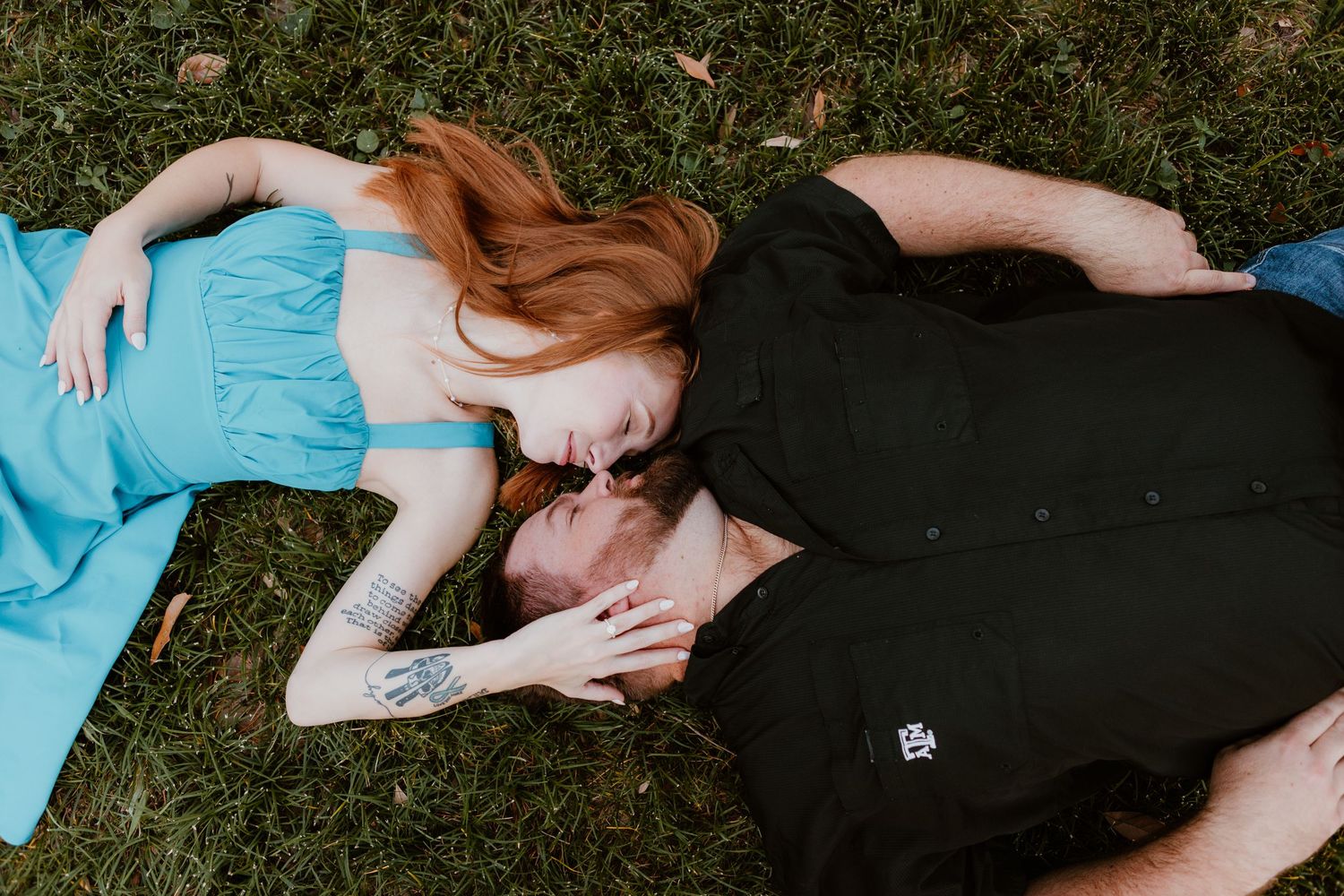 Person in black dress lies on grass during golden hour sunlight in artistic outdoor portrait series.