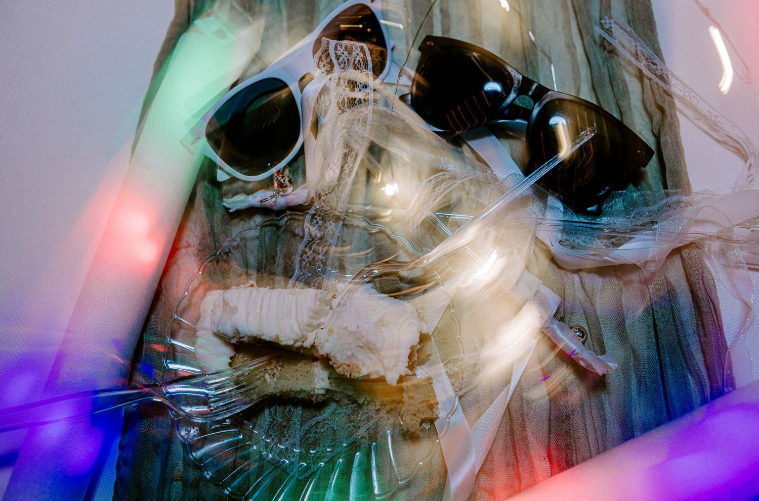 Abstract artistic photo of sunglasses surrounded by colorful bokeh lights and reflective materials.