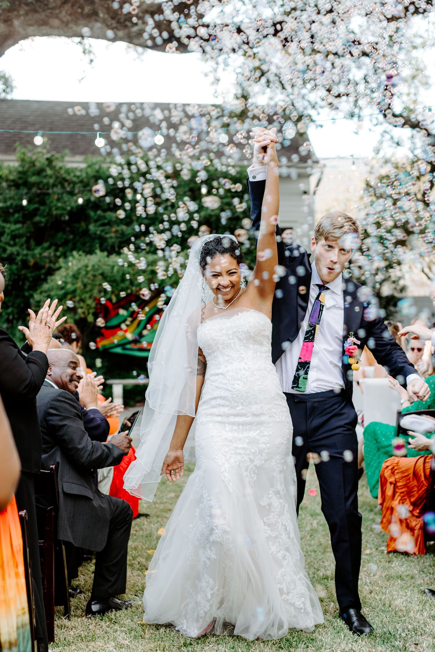 Bride and Groom celebrates saying I do with bubbles and laughter during a joyful garden ceremony celebration in New Orleans.
