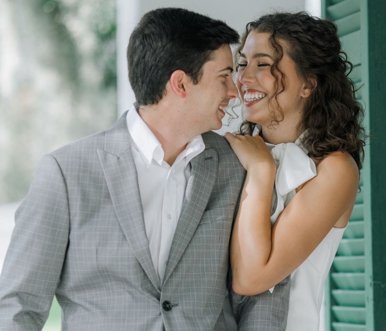 A romantic couple shares intimate moments in a series of photos against a green shuttered wall.