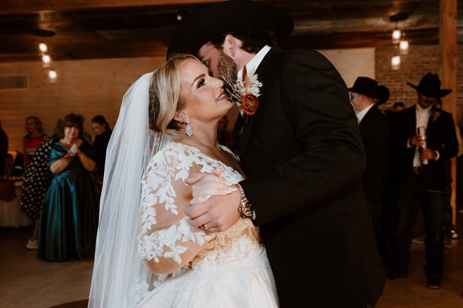 Bride and groom share romantic first dance kiss at rustic western wedding reception.