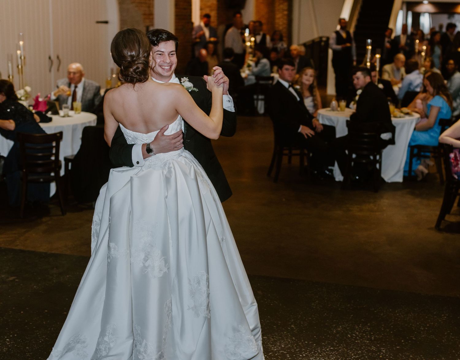 Bride and groom share their first dance at elegant candlelit wedding reception venue.