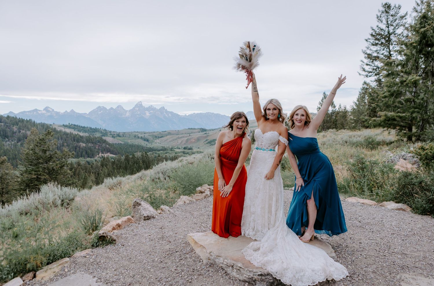 Three women celebrate at mountain wedding with Grand Teton views behind them.
