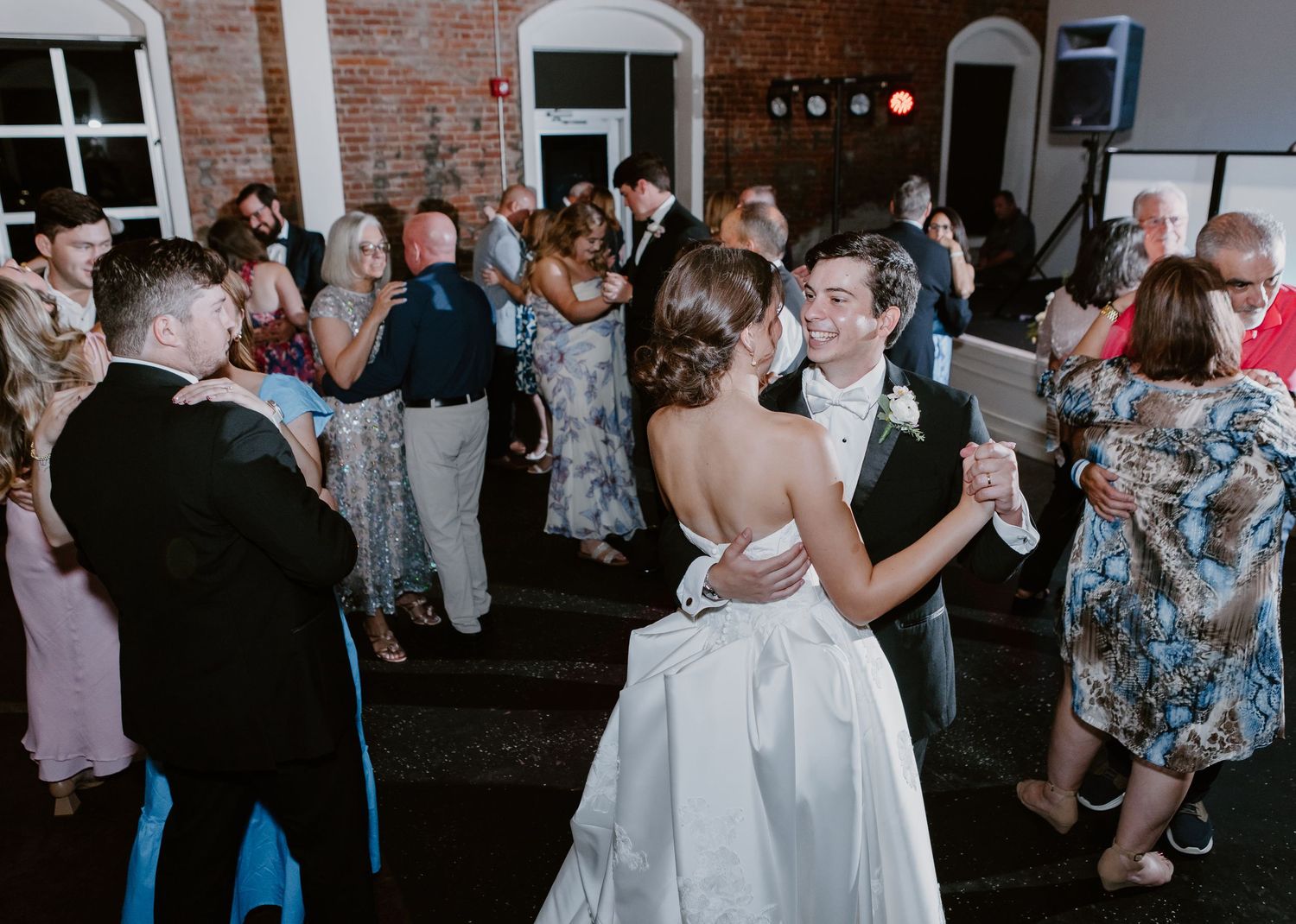 Bride and groom share their first dance surrounded by guests at an elegant wedding reception venue.