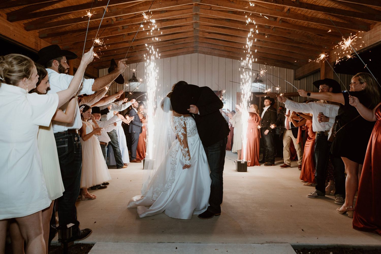 Bride and groom share a romantic kiss during a sparkler exit at their rustic barn wedding reception.