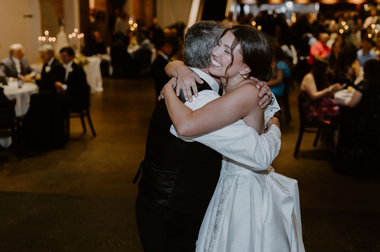 Bride shares emotional hug with guest during wedding reception celebration.