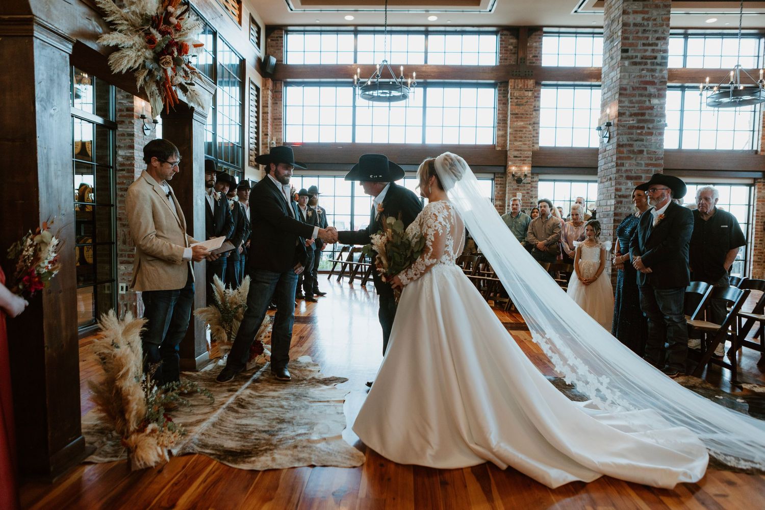 Bride and groom exchange vows at elegant indoor wedding ceremony with exposed brick walls and wooden floors.