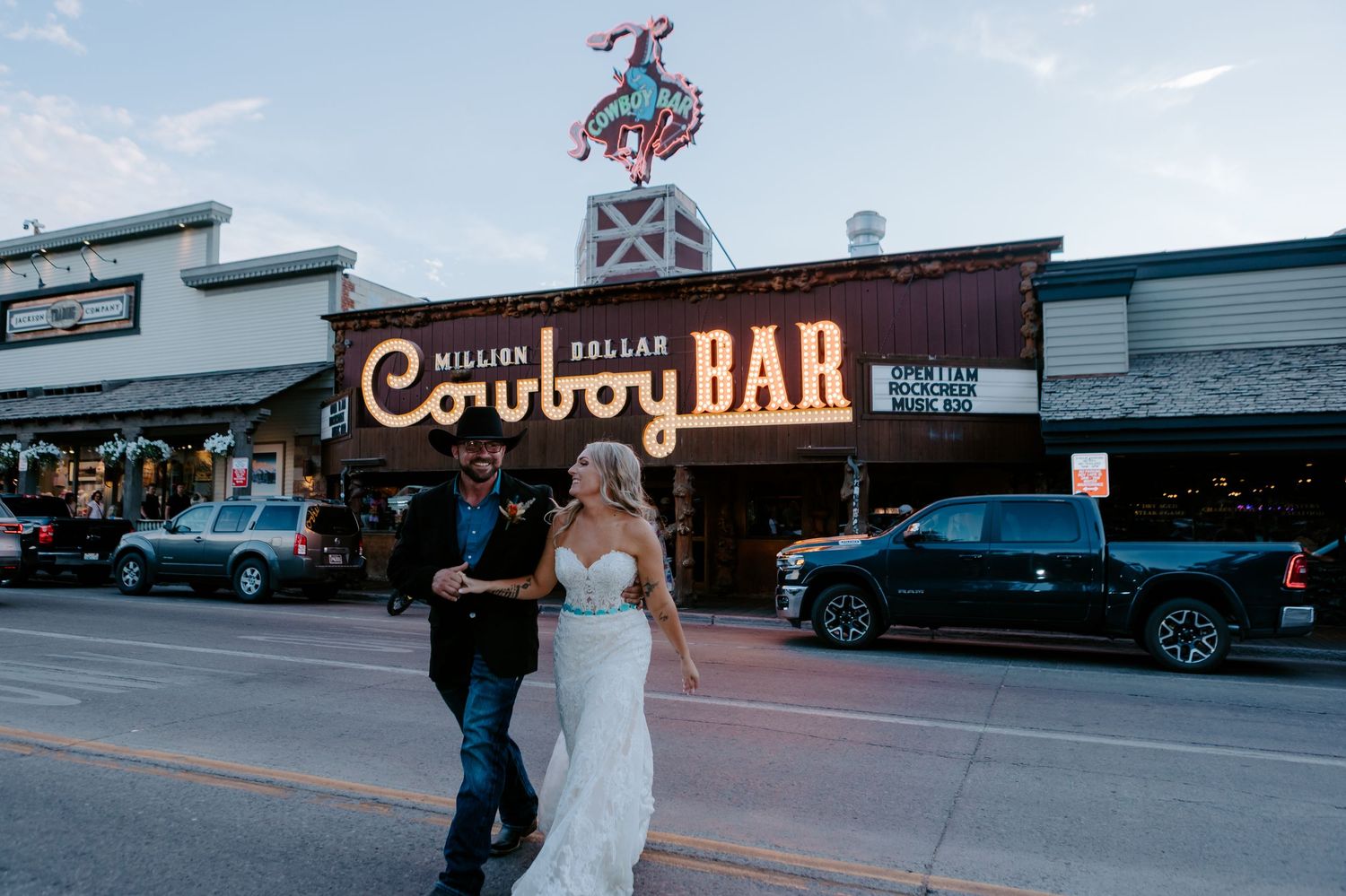 Bride and groom pose in front of the iconic Million Dollar Cowboy Bar neon sign in Jackson Hole, Wyoming.