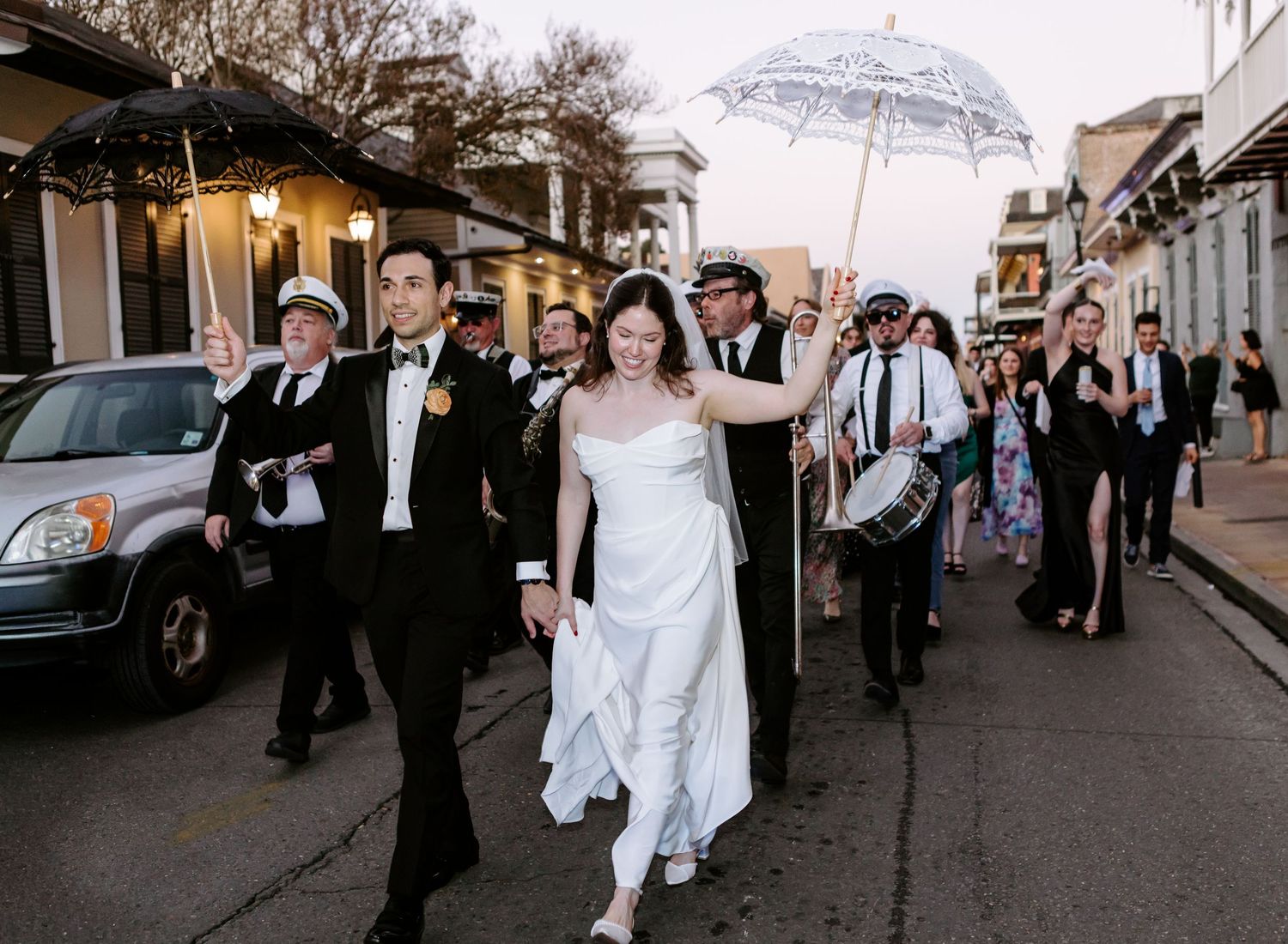 Wedding party doing the second line in New Orleans on the  French Quarter  while holding white umbrellas during a rainy celebration.