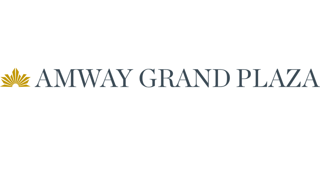Modern hotel exterior with illuminated Amway Grand Plaza signage on top of an elegant high-rise building at night.