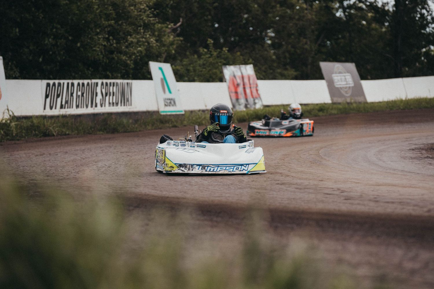 Go-karts battle for position at Poplar Grove Speedway, kicking up dust on a tight turn during heat races
