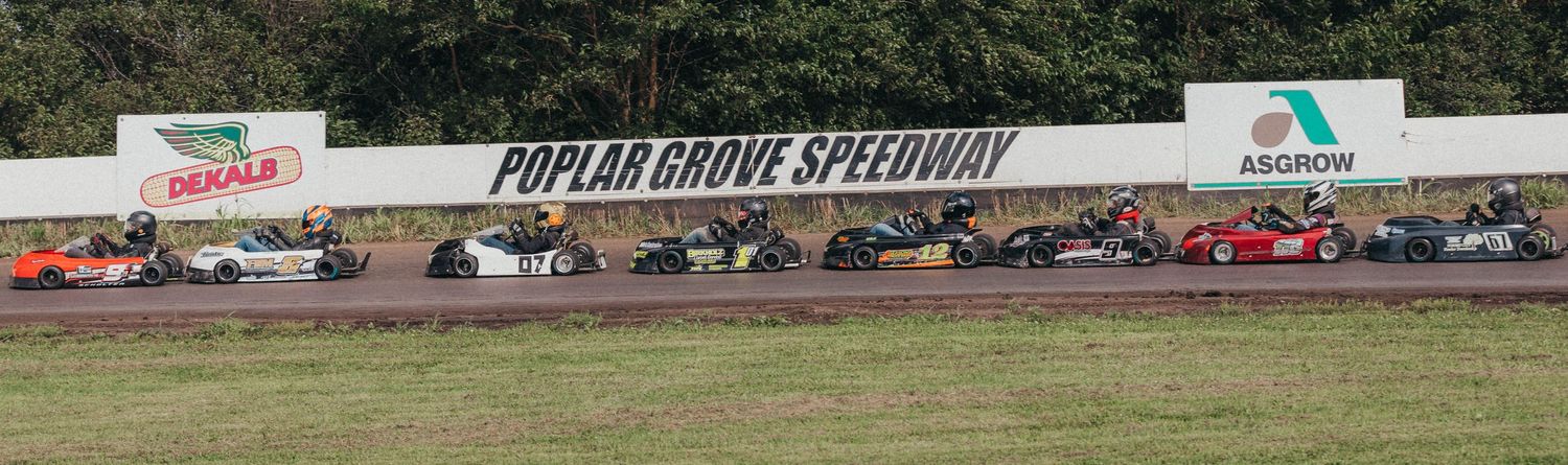 Go-karts battle for position at Poplar Grove Speedway, kicking up dust on a tight turn during heat races