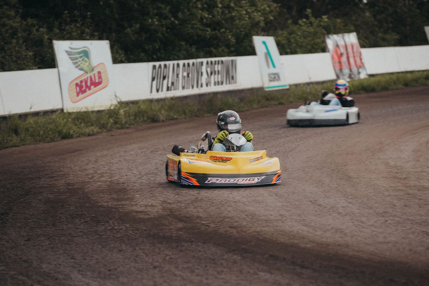 Go-karts battle for position at Poplar Grove Speedway, kicking up dust on a tight turn during heat races