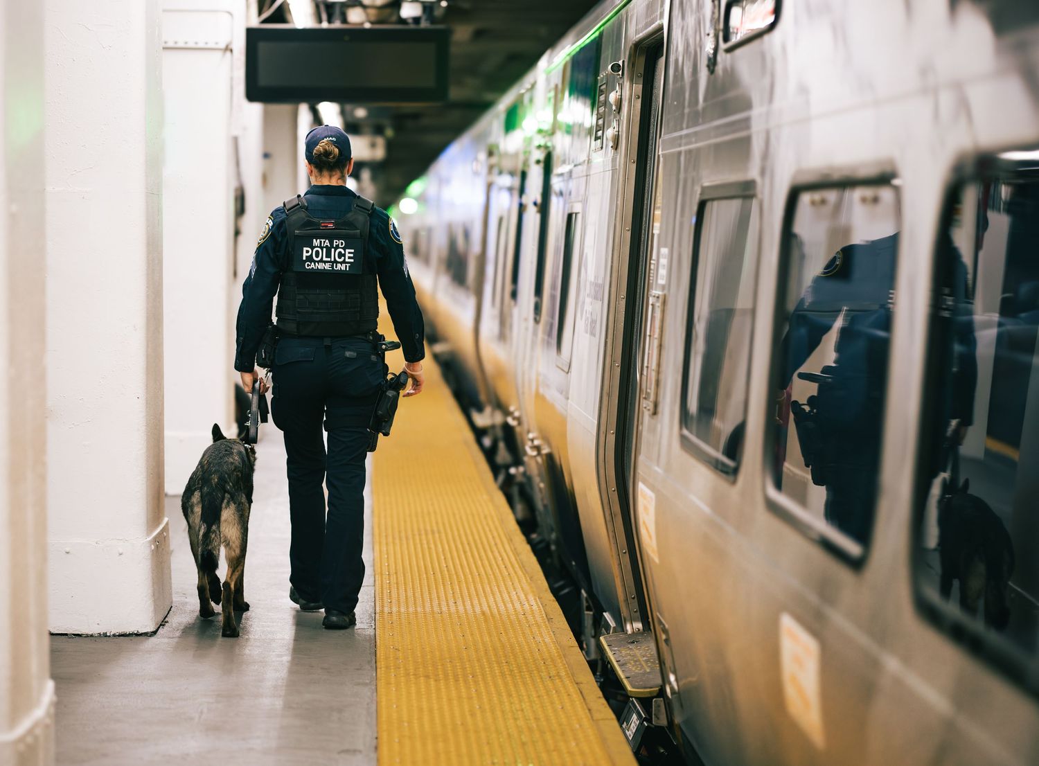 People walking on a subway platform alongside a train car in an urban transit station.