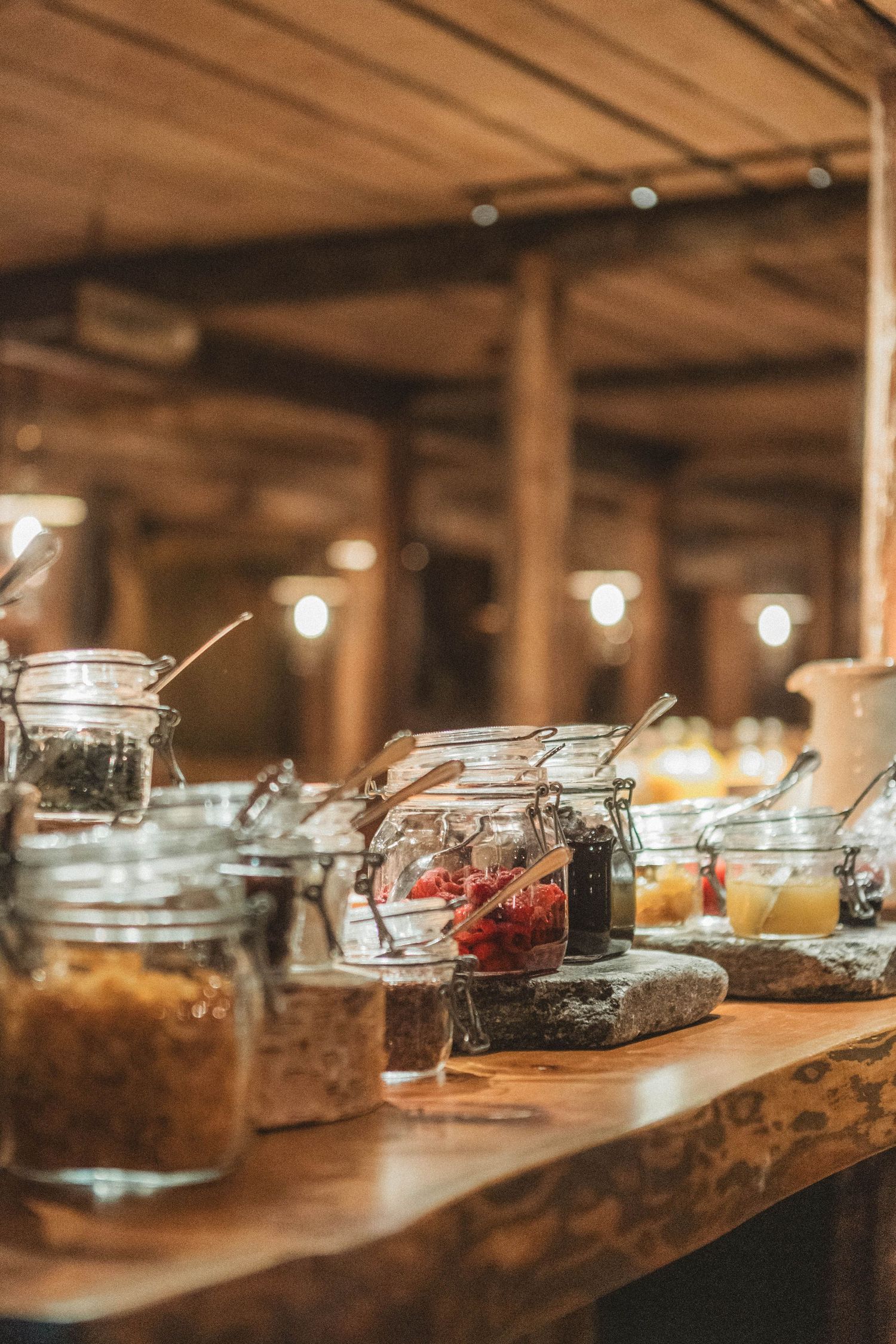 Rustic display of glass jars filled with various ingredients on a wooden counter with warm ambient lighting.