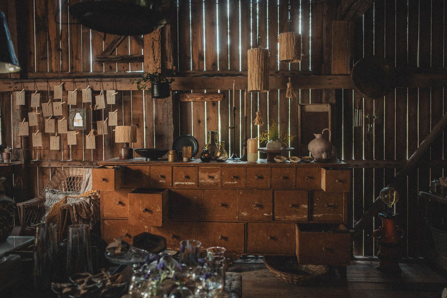 Vintage wooden apothecary cabinet with multiple drawers in a dimly lit rustic workshop setting.