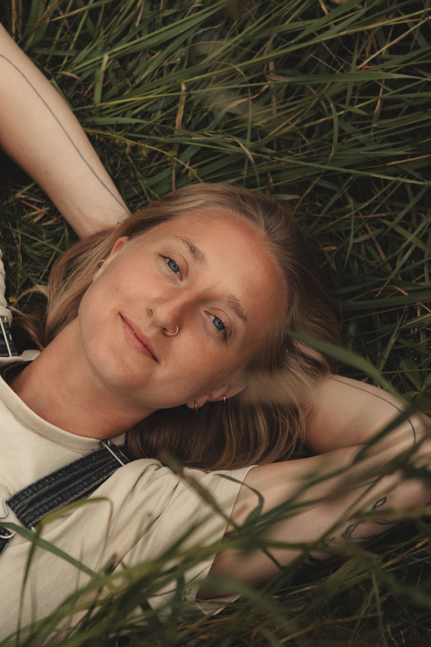 A peaceful moment lying in tall grass wearing a white top with natural lighting.