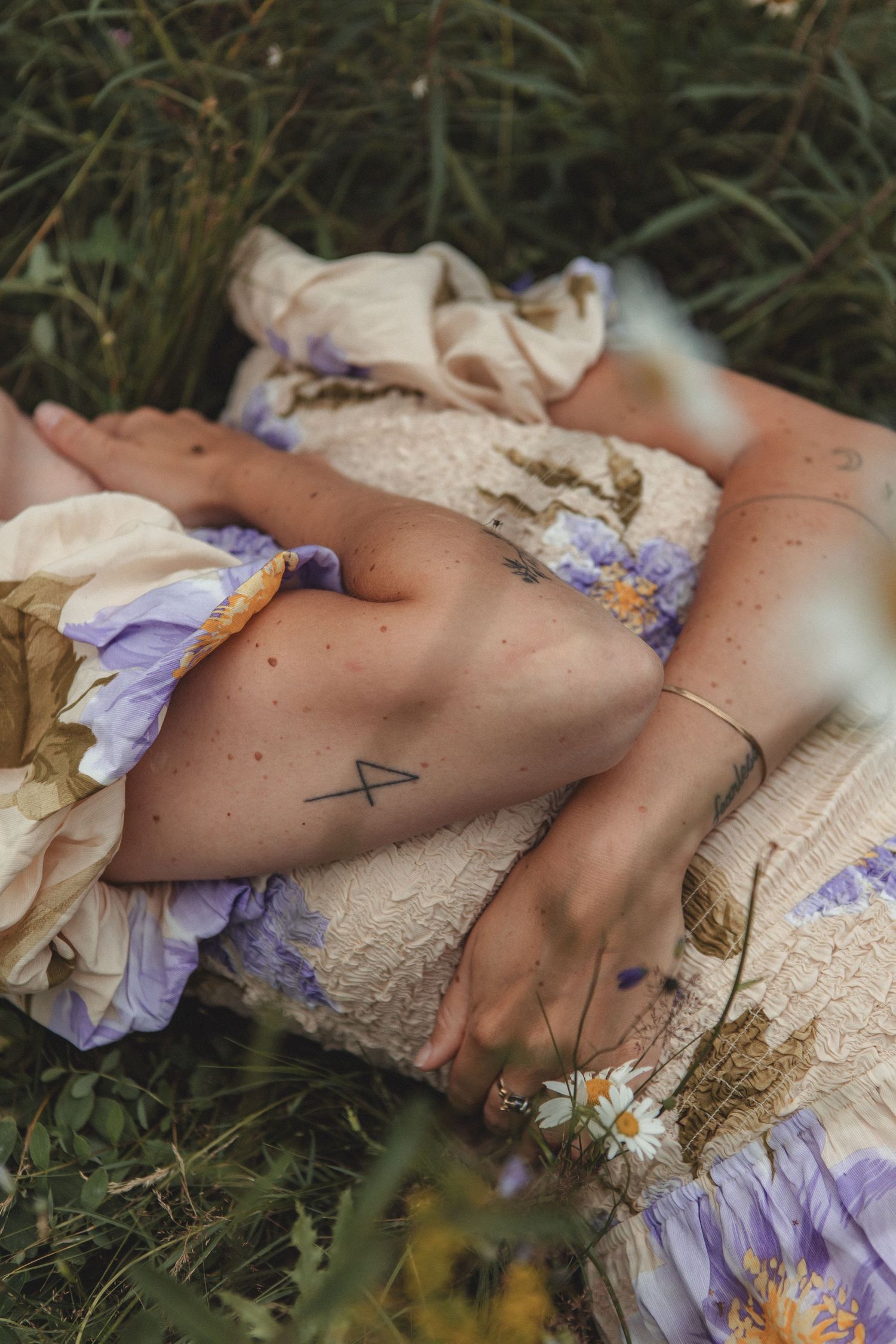 Artistic detail shot of arms and flowers in summer meadow setting.