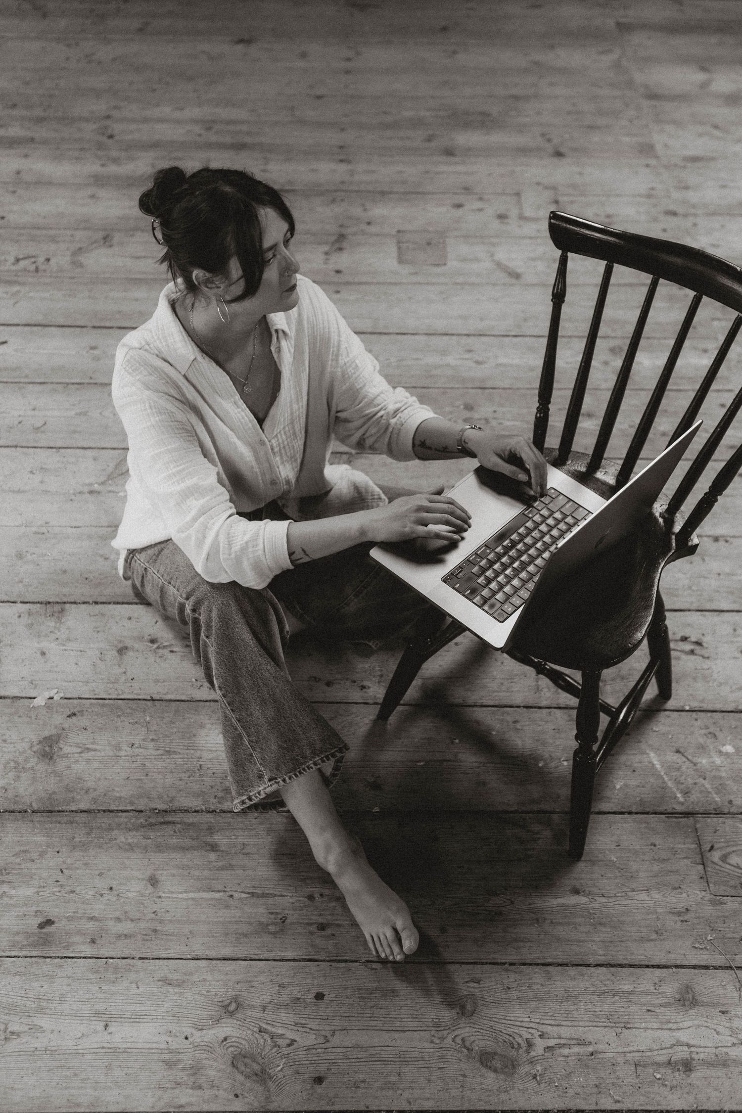 Black and white photo series showing someone using laptop while sitting on dark wooden chair.