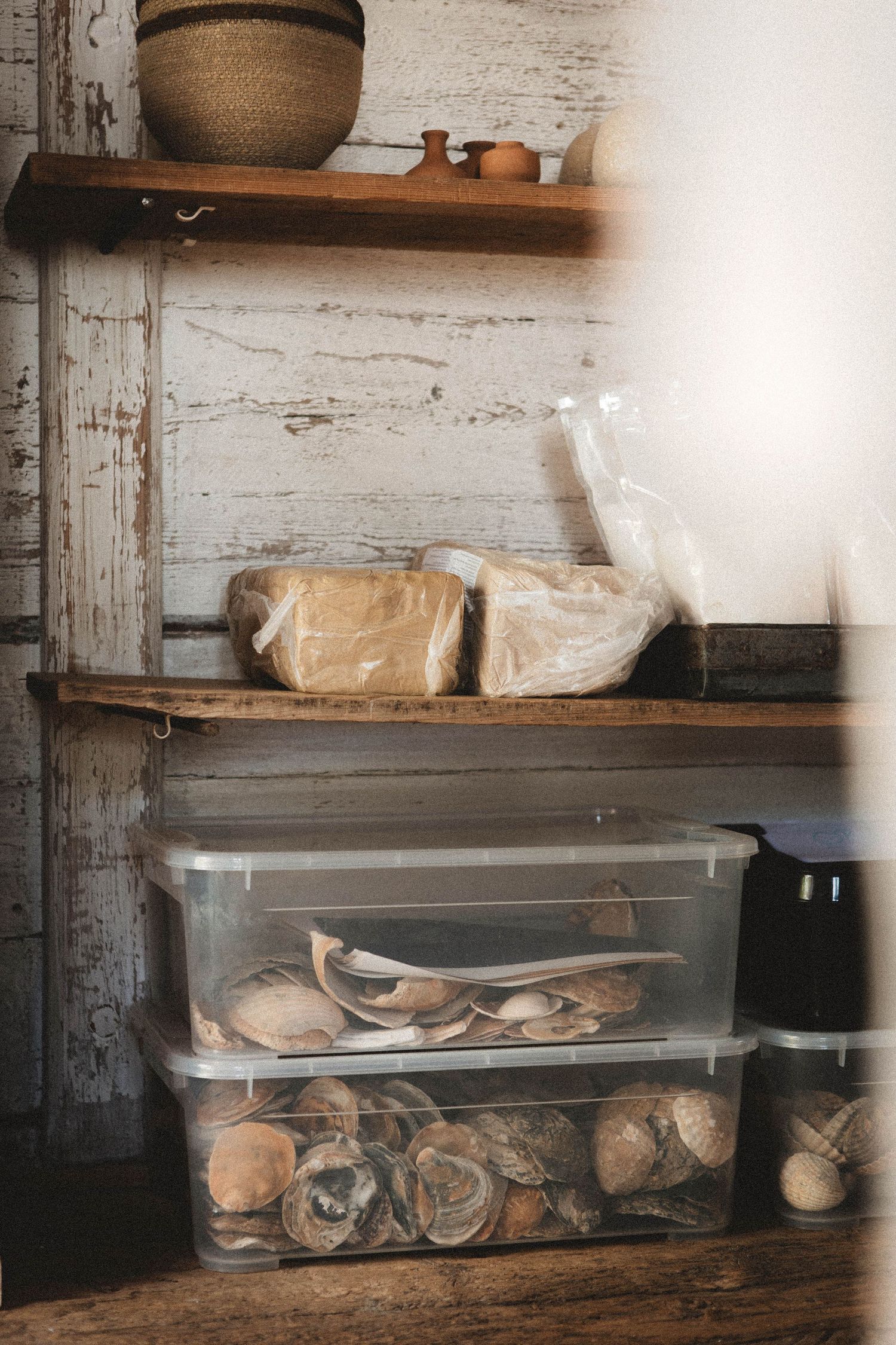 Rustic wooden shelves with storage containers and pottery displayed in farmhouse style.