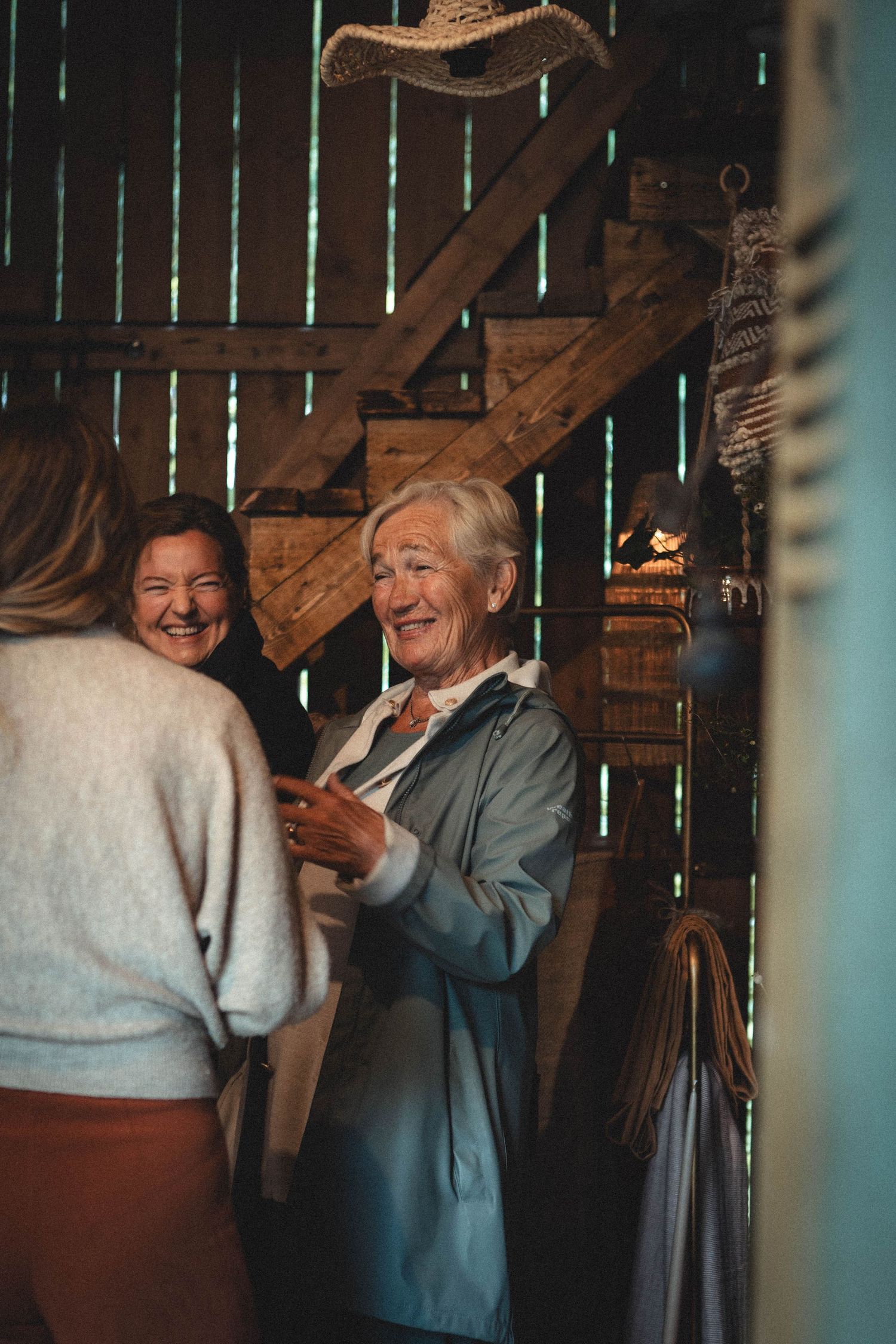 Cozy conversation in rustic barn interior with wooden staircase visible.