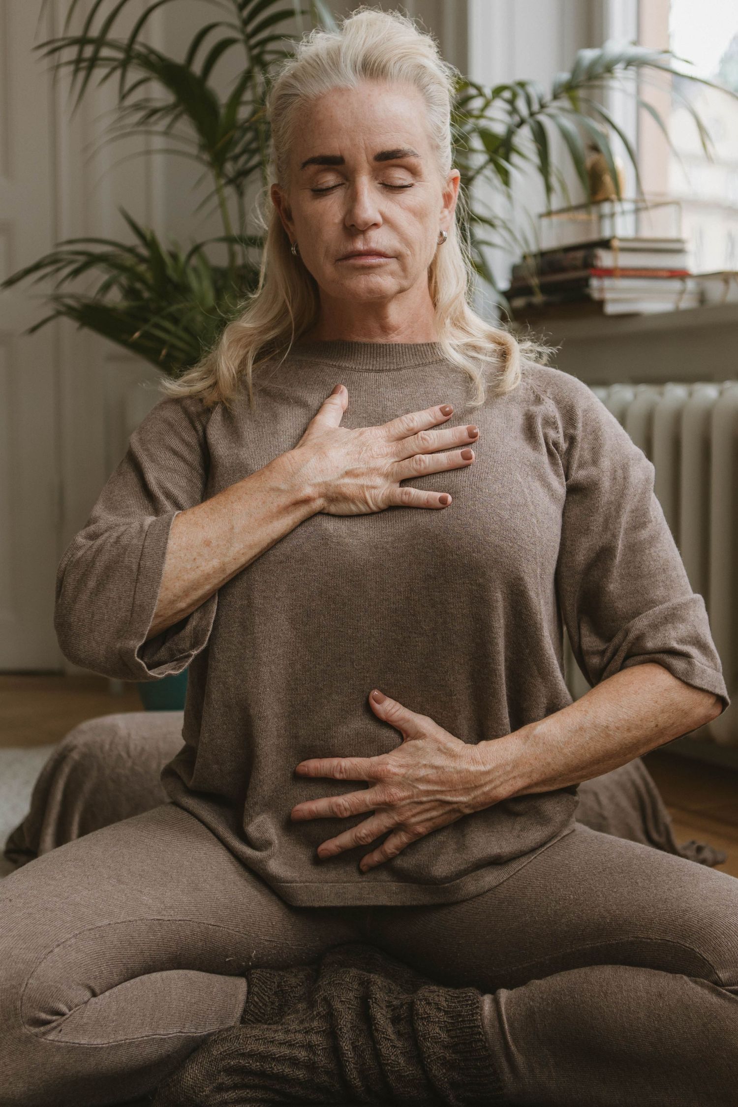 Person performs gentle breathing exercises in comfortable clothing during meditation practice.