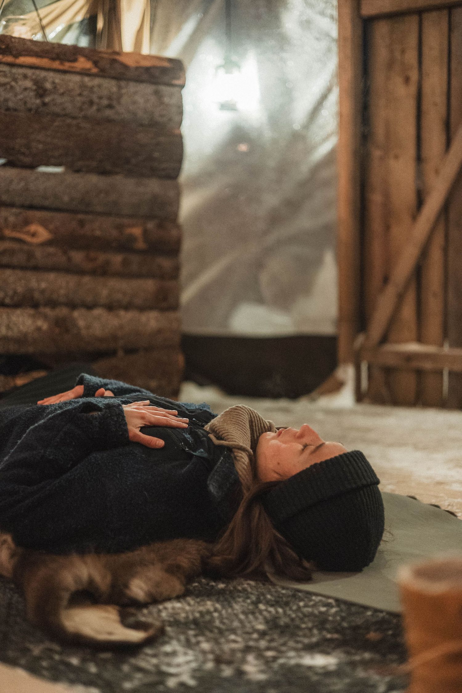 Someone resting on a cozy blanket in a rustic cabin with wooden walls and natural light.