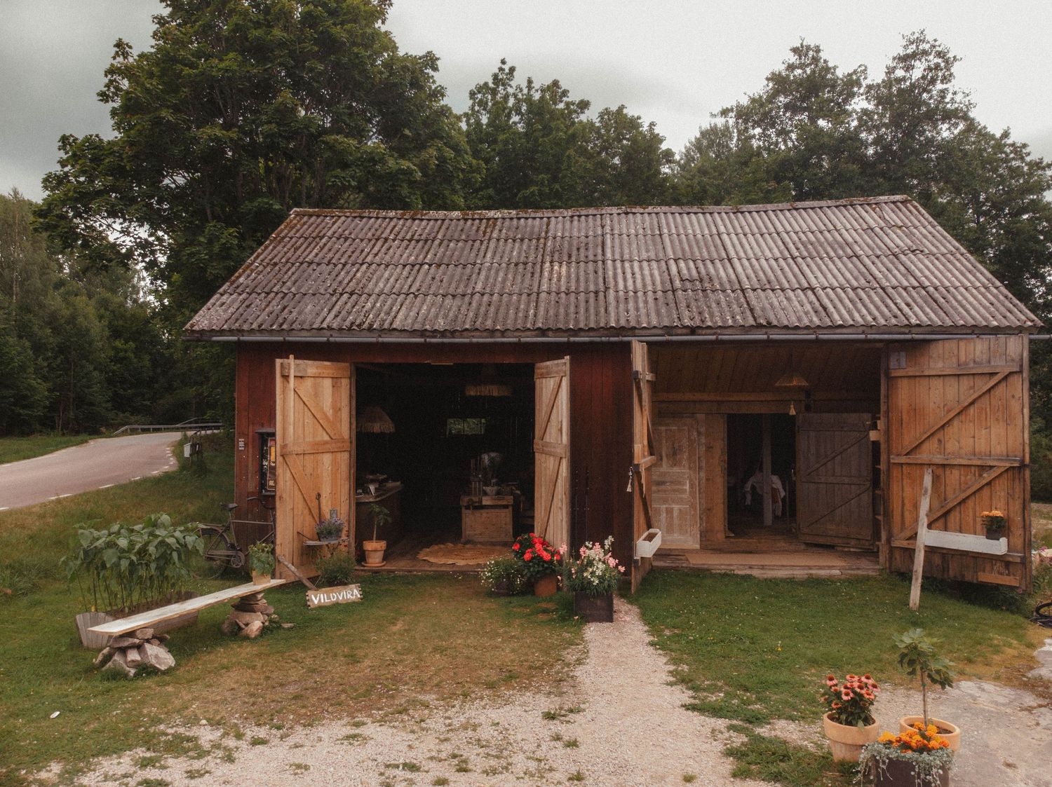 Rustic wooden barn with open doors and autumn decorations along a garden path.