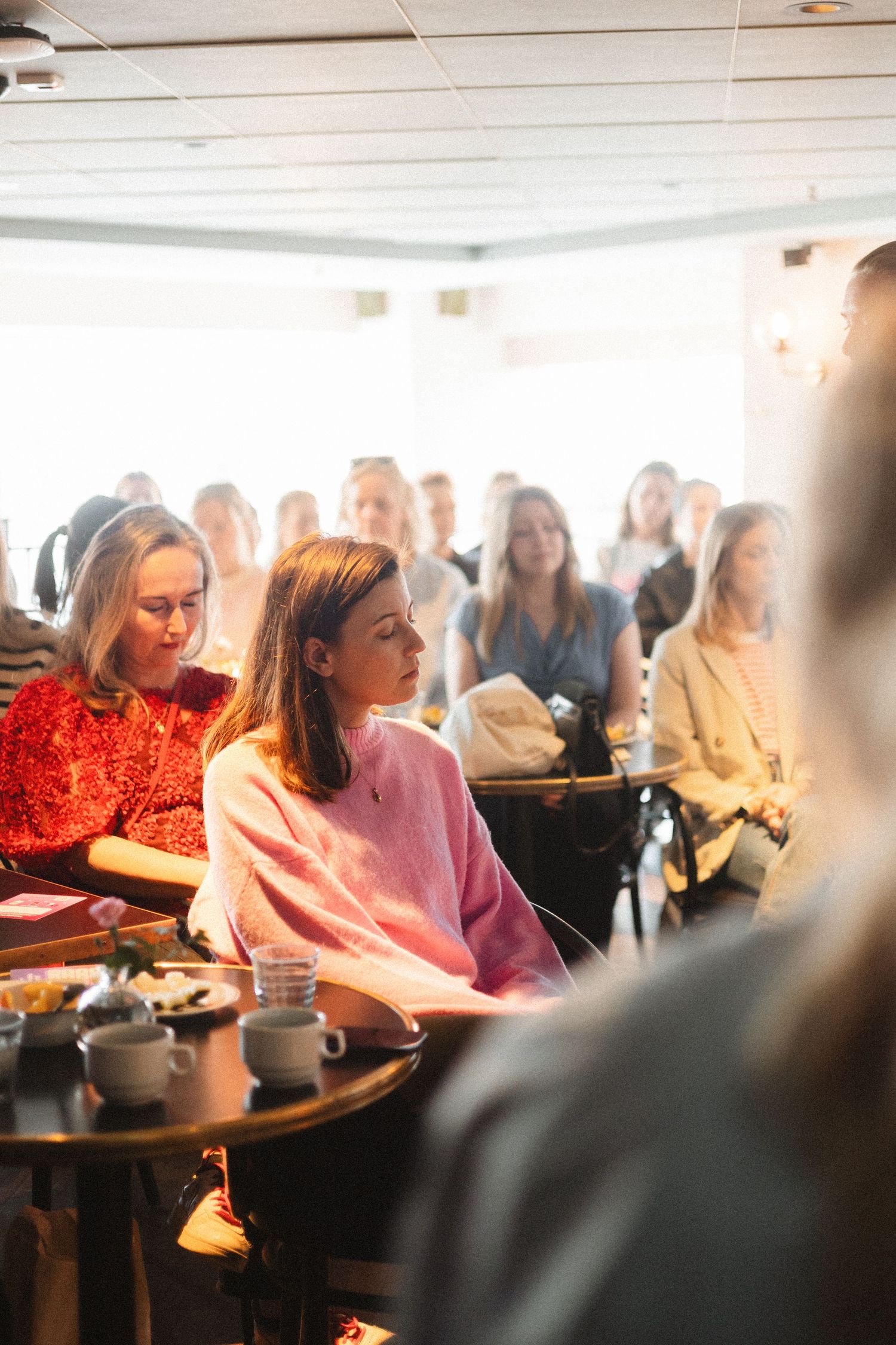 People gathered in a cozy cafe space listen attentively during a casual meeting or presentation.