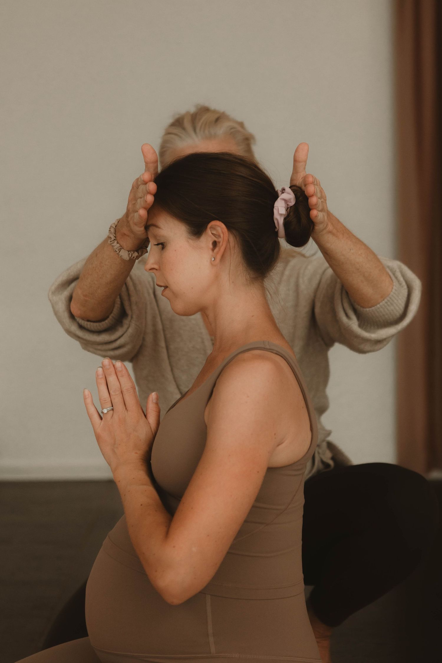 A therapeutic healing session shows hands gently placed on the recipient's head during a meditative moment.