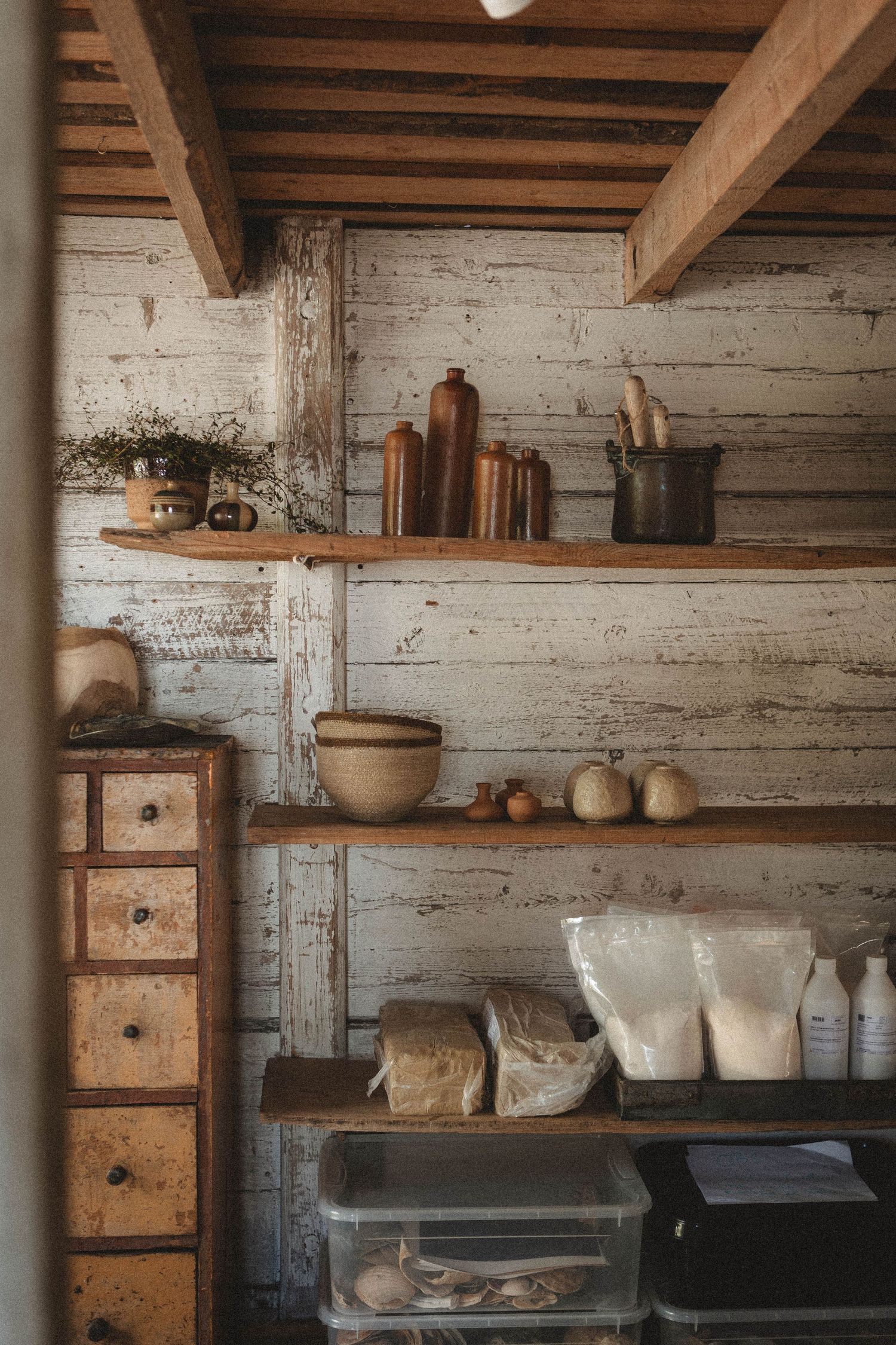 Rustic shelving unit with wooden drawers displaying vintage kitchen items and containers.