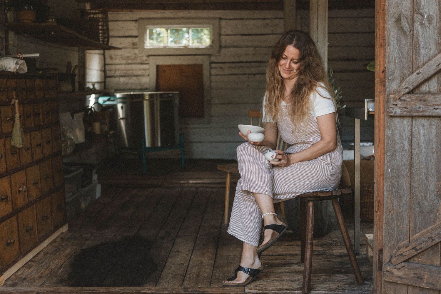 Rustic barn interior scene with wooden stool and vintage lighting.
