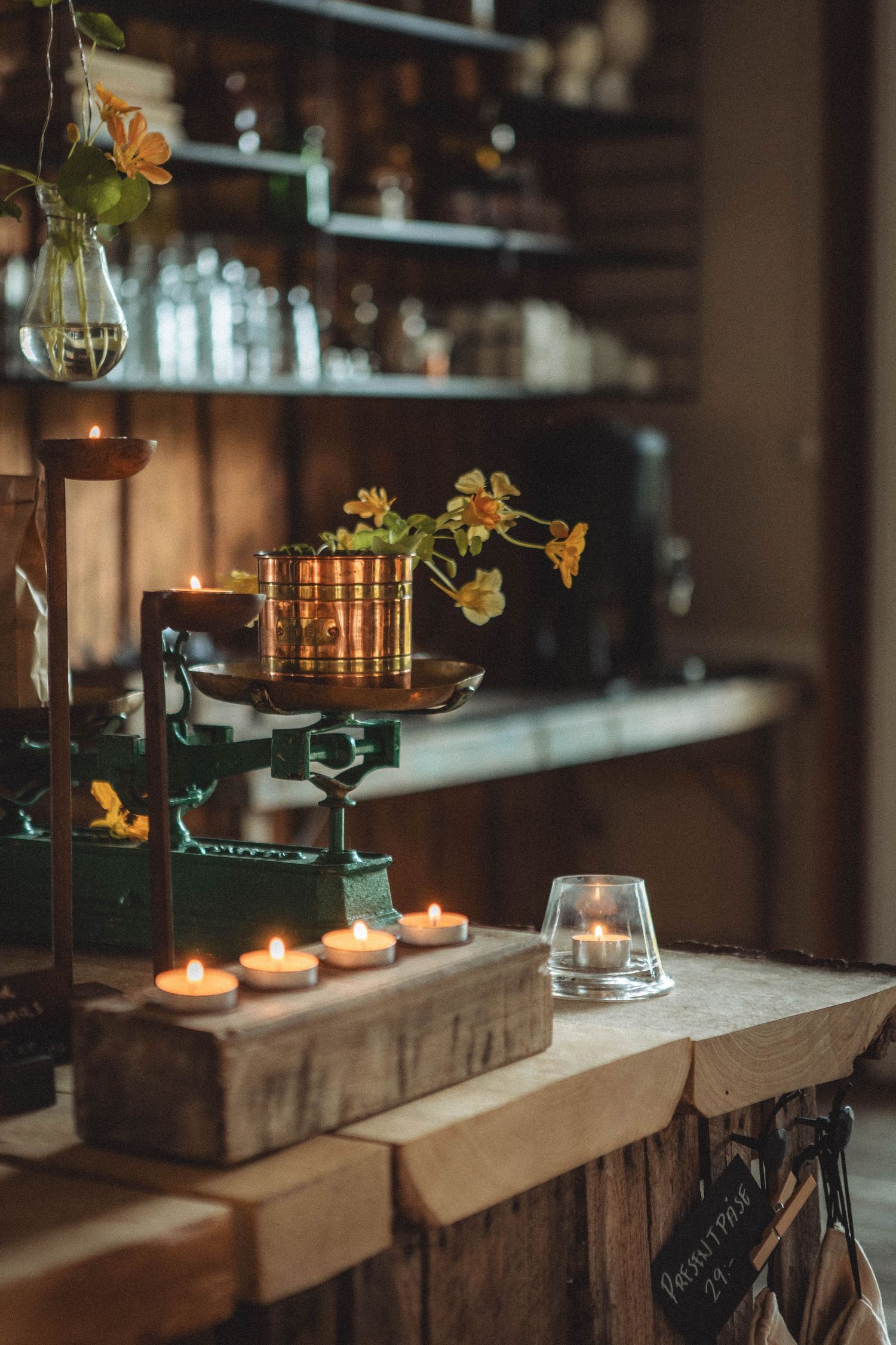 Cozy bar counter with candlelit decor, copper vessels, and yellow flowers in vases.