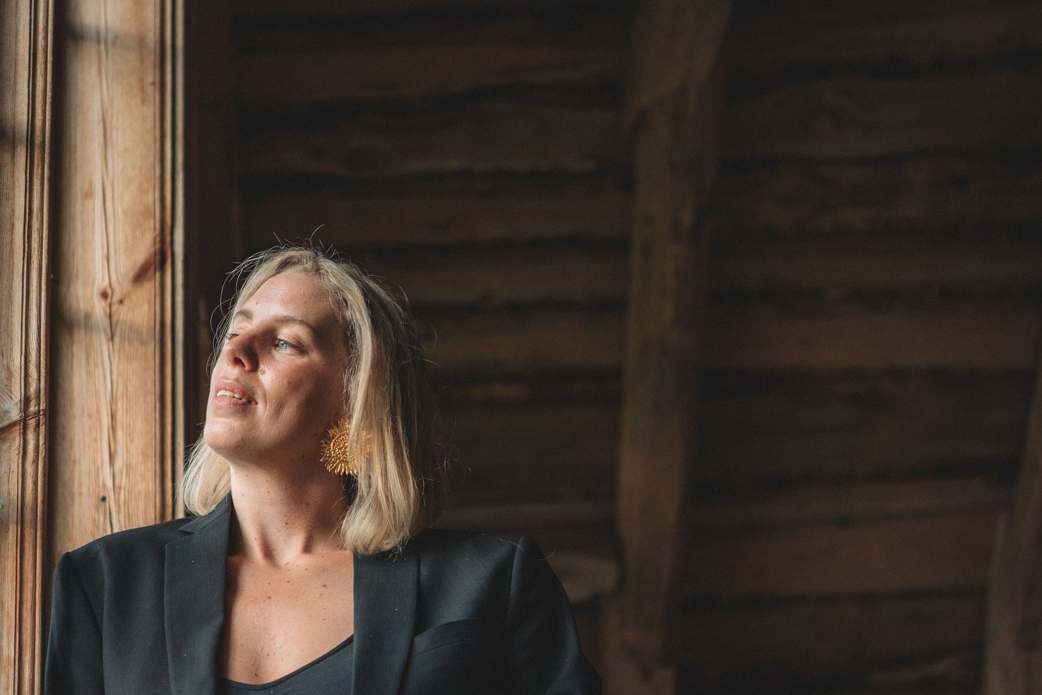 Atmospheric portrait against rustic window with natural wood beams.