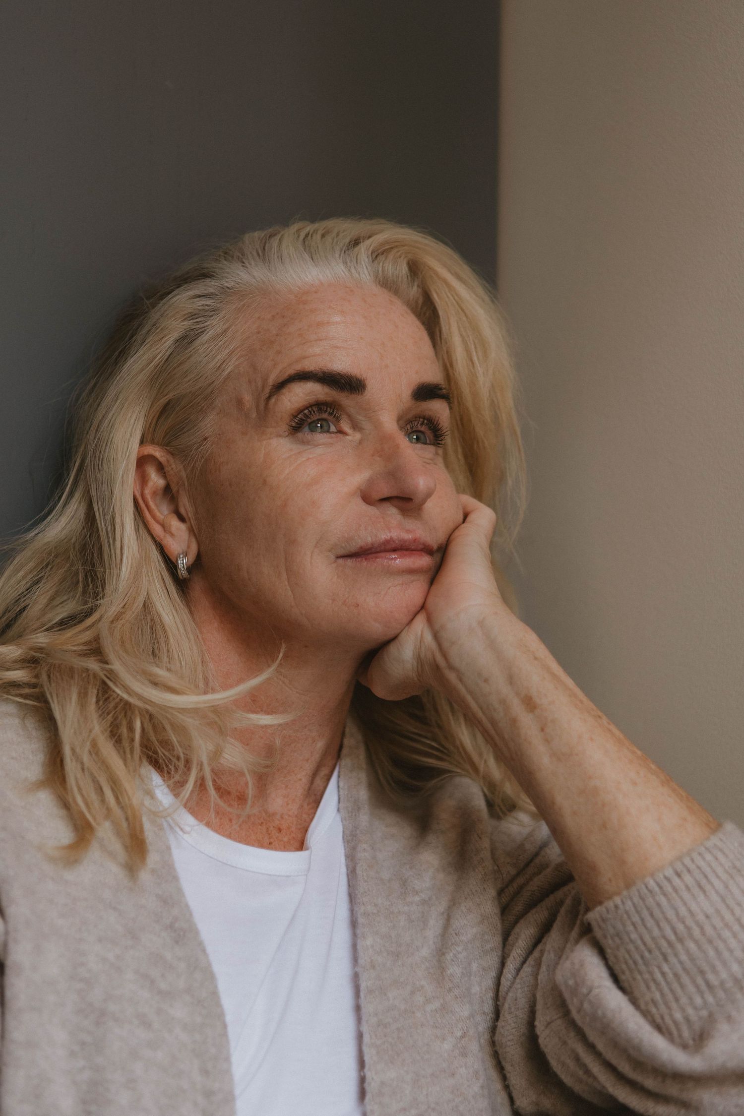 Person in casual attire reflects thoughtfully while resting head on hand.