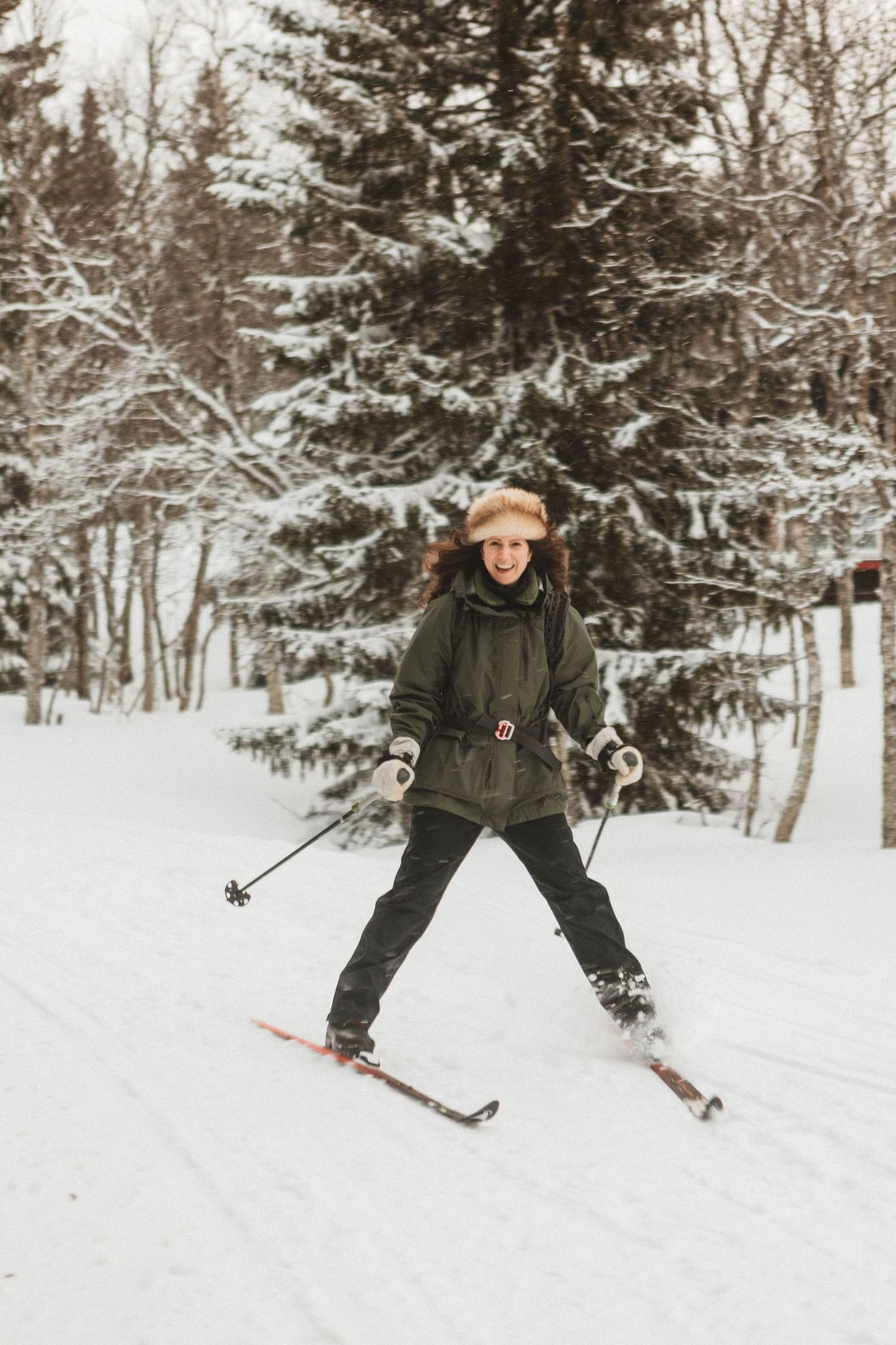 A skier glides down a snowy slope surrounded by snow-covered evergreen trees in winter.